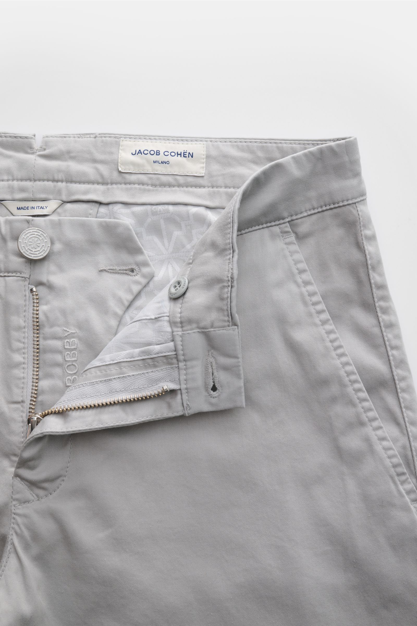 Jacob Cohen Chino 'Bobby' hellgrau aus feinem Baumwoll-Twill, slim Fit, elastisch, weicher Griff, geöffnet mit Reißverschluss und Bundknopf, frontal fotografiert.