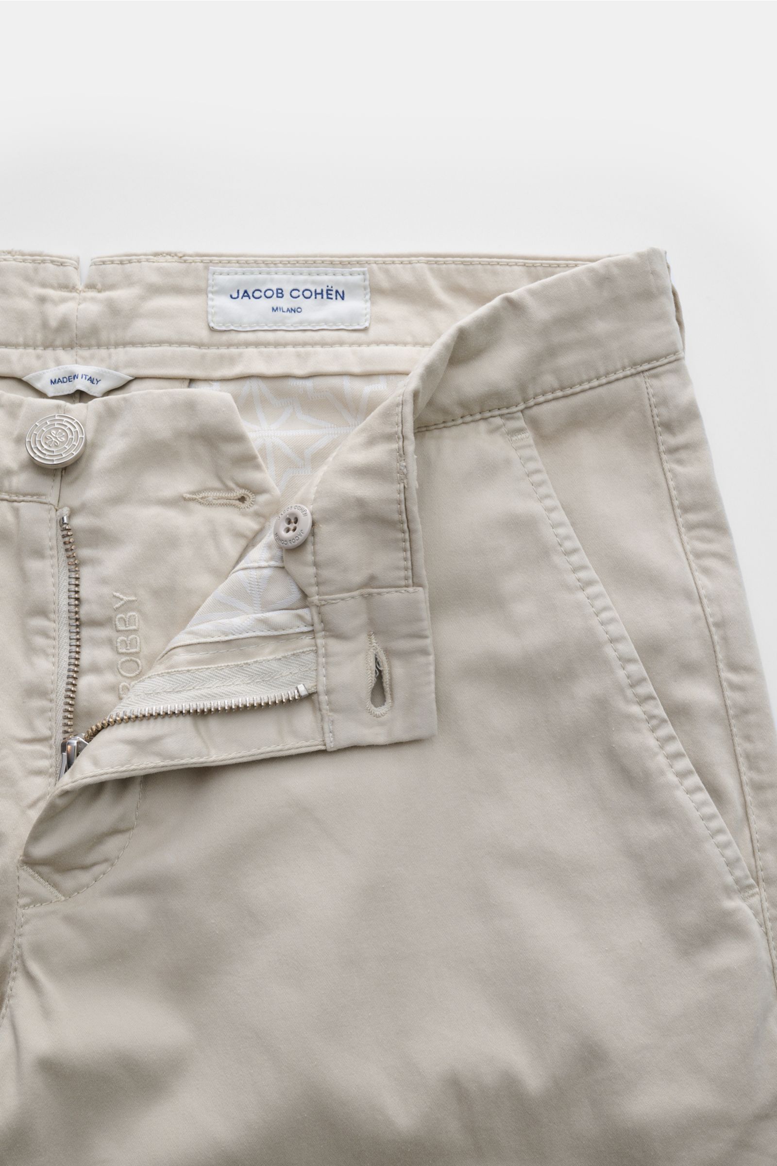 Jacob Cohen Chino 'Bobby' beige, frontal fotografiert, aus softem Baumwoll-Twill, Slim Fit, mit Reißverschluss, Bundknopf, französischen Taschen, Münztasche, Knopf-Gesäßtaschen, Verloursleder-Patch.