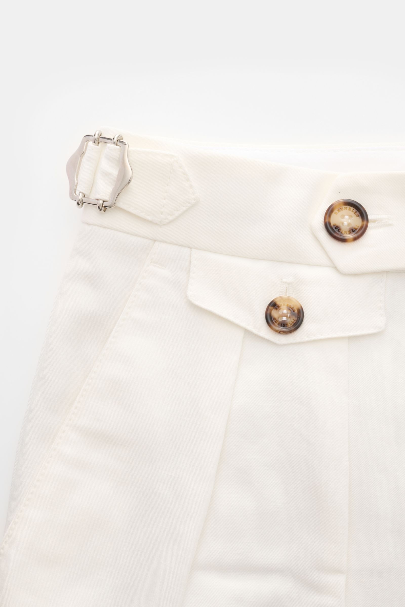 Brunello Cucinelli Hose offwhite close-up from the front top showing cotton-linen twill fabric, side adjuster, buttoned waistband, and pleats. Eleganz mit jedem Schritt: Die BRUNELLO CUCINELLI Hose aus Baumwolle und Leinen verspricht höchsten Tragekomfort