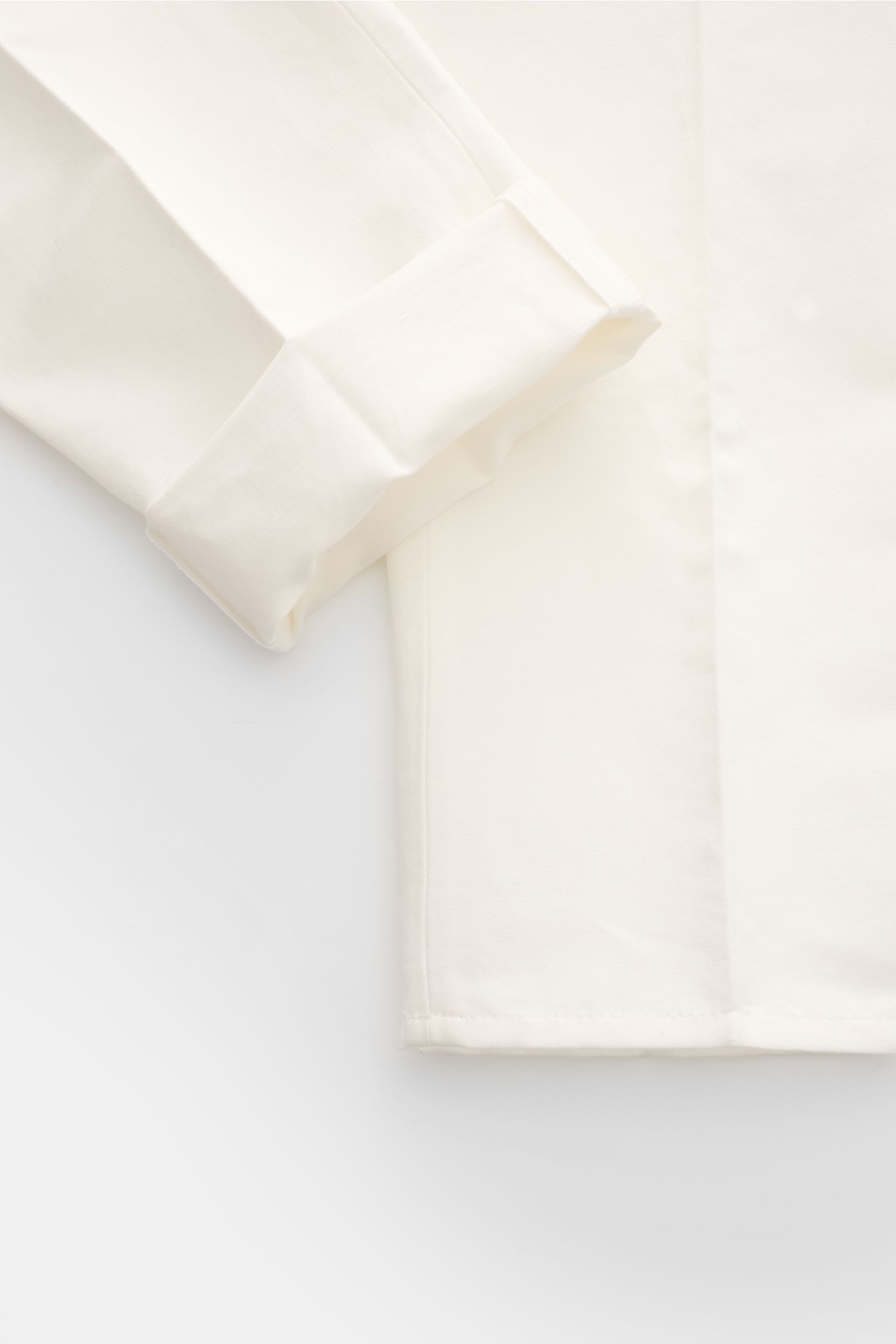 Close-up of the cuff and lower sleeve of the Brunello Cucinelli Hose offwhite, photographed from a top-down perspective, showing finely structured cotton-linen twill fabric with a smooth touch. 

Eleganz mit jedem Schritt: Die BRUNELLO CUCINELLI Hose a