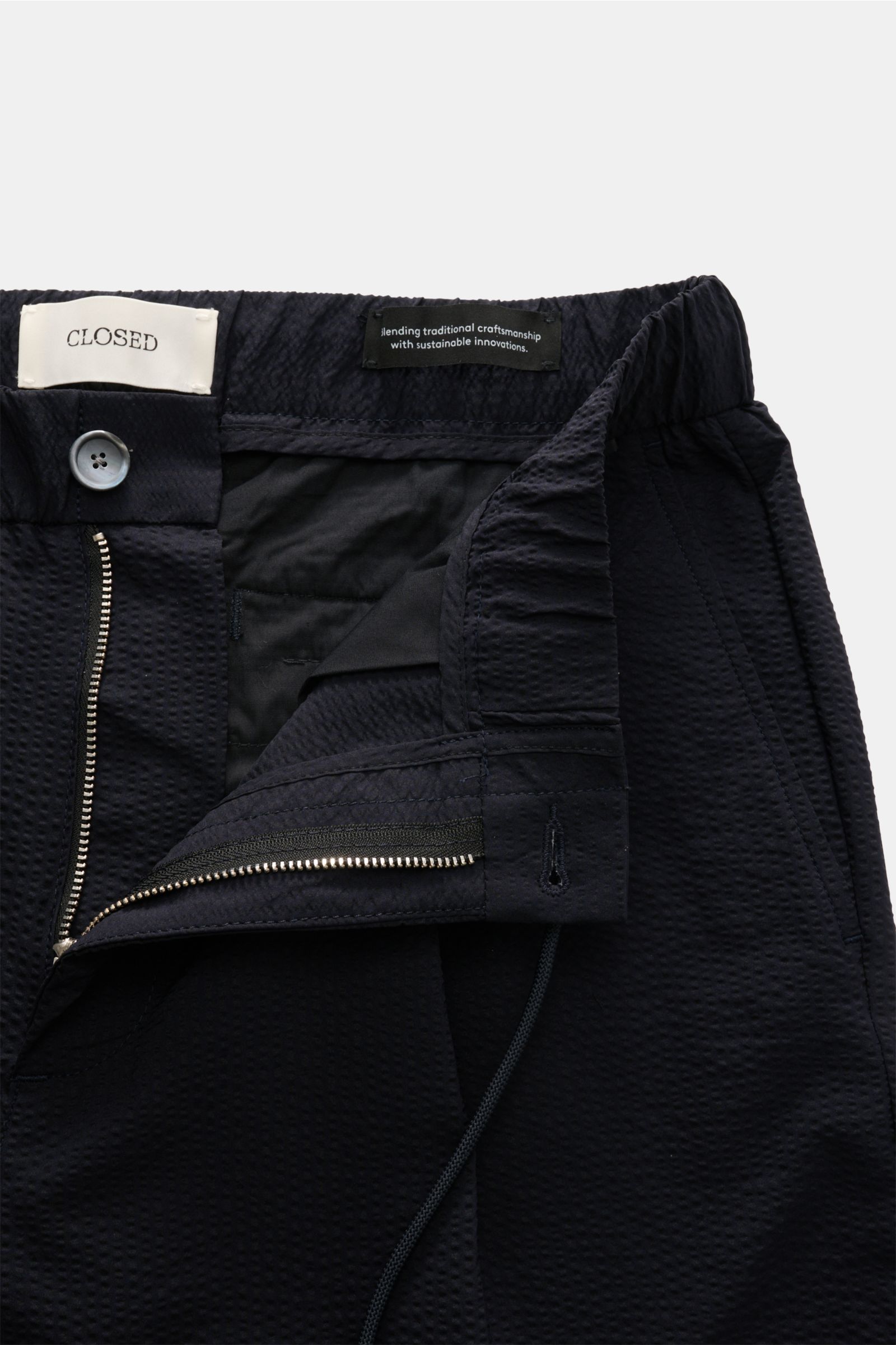Nahaufnahme der geöffneten Taille der Closed Jogpants 'Vigo' dark navy aus sommerlichem Seersucker mit Reißverschluss, Bundknopf und elastischem Tunnelzug.