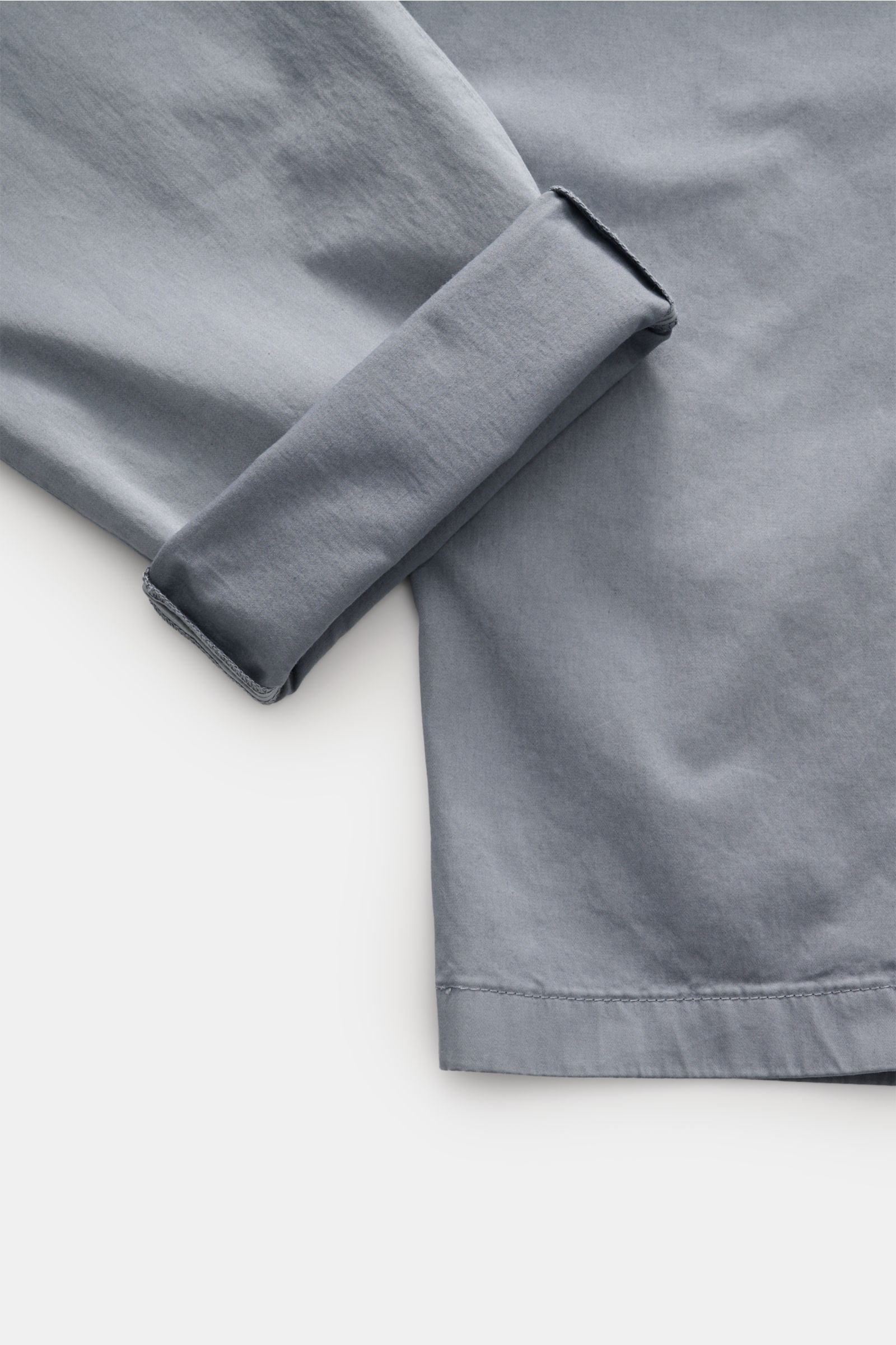 Nahaufnahme der leicht elastischen, rauchblauen Closed Baumwollhose 'Bergen Tapered' im Tapered Fit, knöchellang, mit umgeschlagenem Bein vom seitlichen Blick.