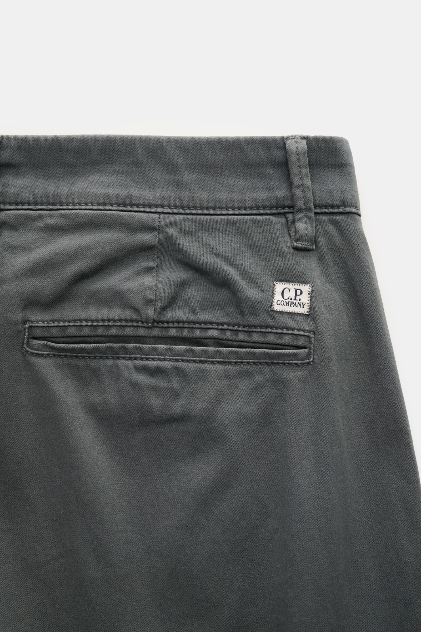 Close-up rear view of C.P. Company Cargohose dunkelgrau in dark gray gabardine cotton with soft touch, regular fit, tapered leg, side seam and cargo pockets, back welt pocket, zipper and button closure, and label-specific lens detail. Urban Utility: Die C