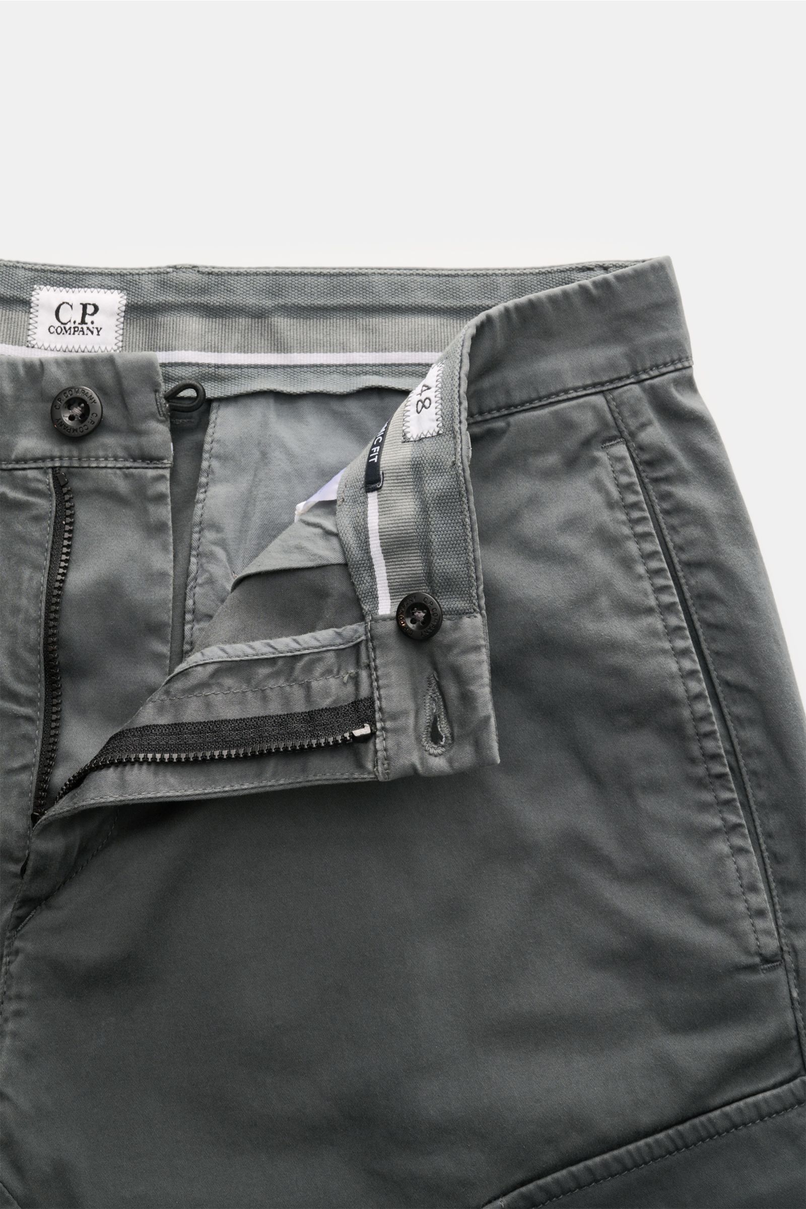 Close-up front view of C.P. Company Cargohose dunkelgrau showing the open zipper and button closure, side seam pocket, and waistband details. Urban Utility: Die Cargohose von C.P. COMPANY kombiniert funktionale Details mit entspanntem Fit und hohem Komfor