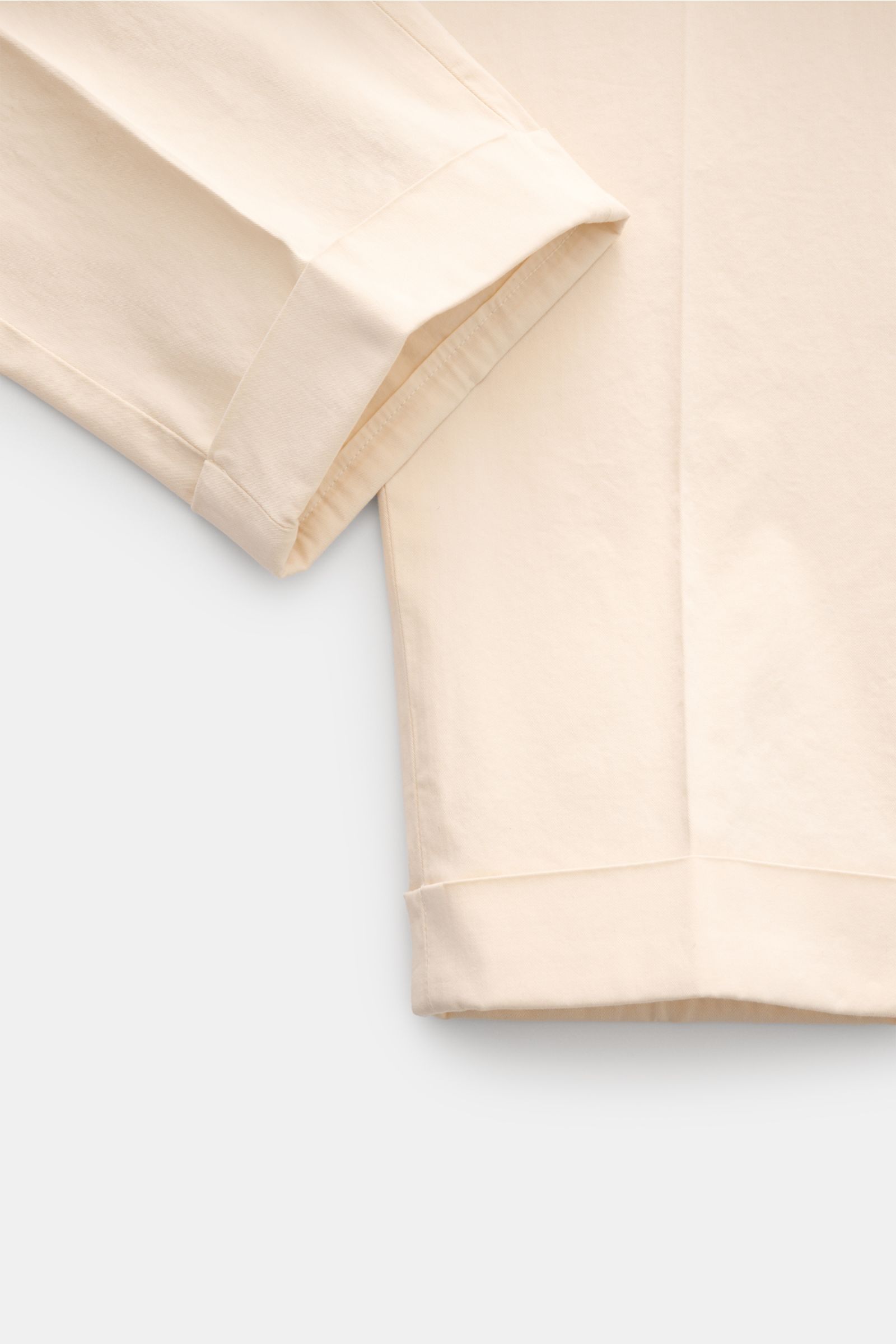 Santaniello Chinos 'Camerota' cream shown from a close-up side angle, featuring fine cotton twill, soft feel, tapered fit, ankle length with fixed hem turn-up, single pleat, French pockets, and back pockets with button flap; casual meets stylish with slig