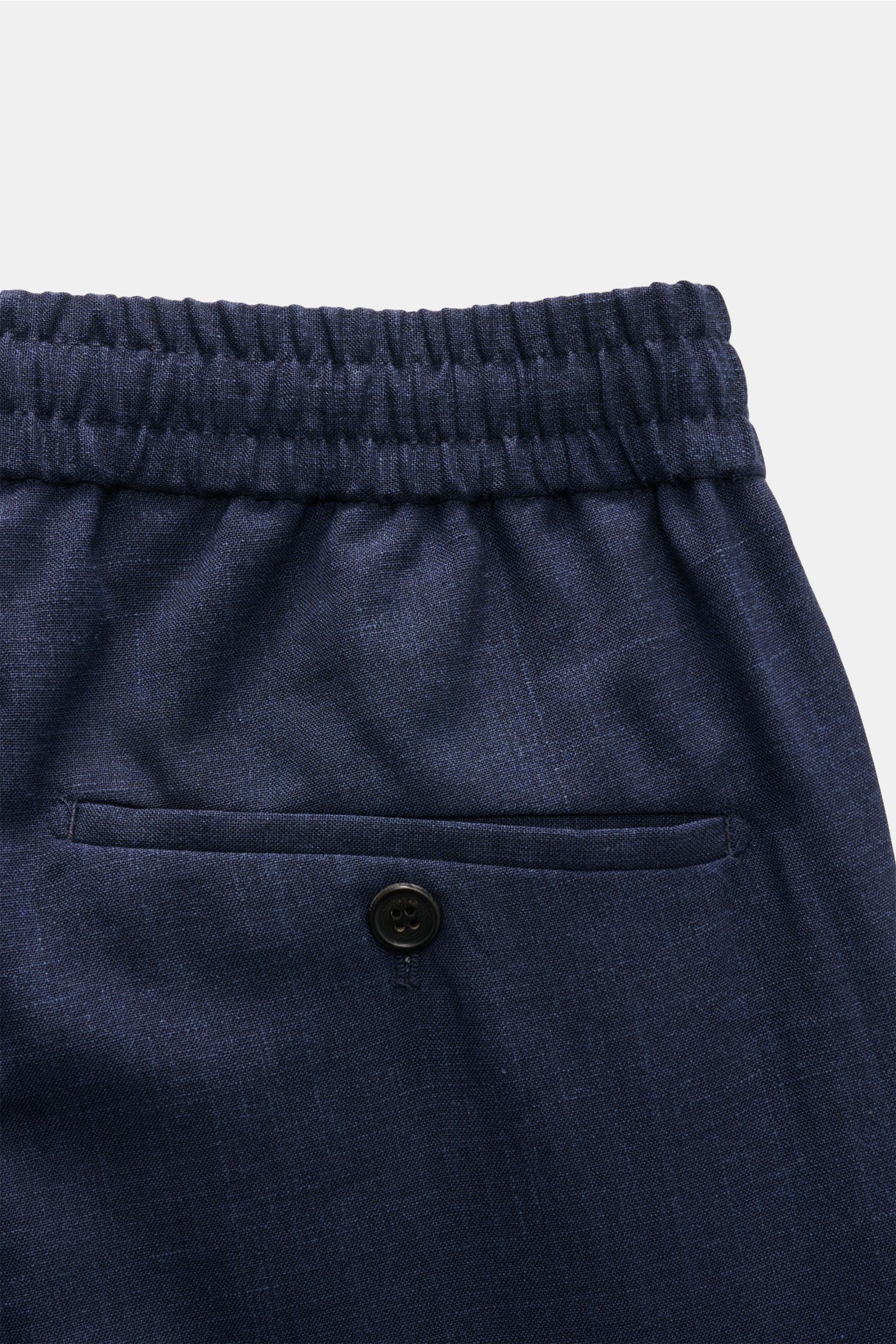 Close-up from above of Incotex Jogger pants dark blue mottled showing elasticated waistband with drawstring, back button pocket, and smooth wool, silk, linen blend fabric. 

