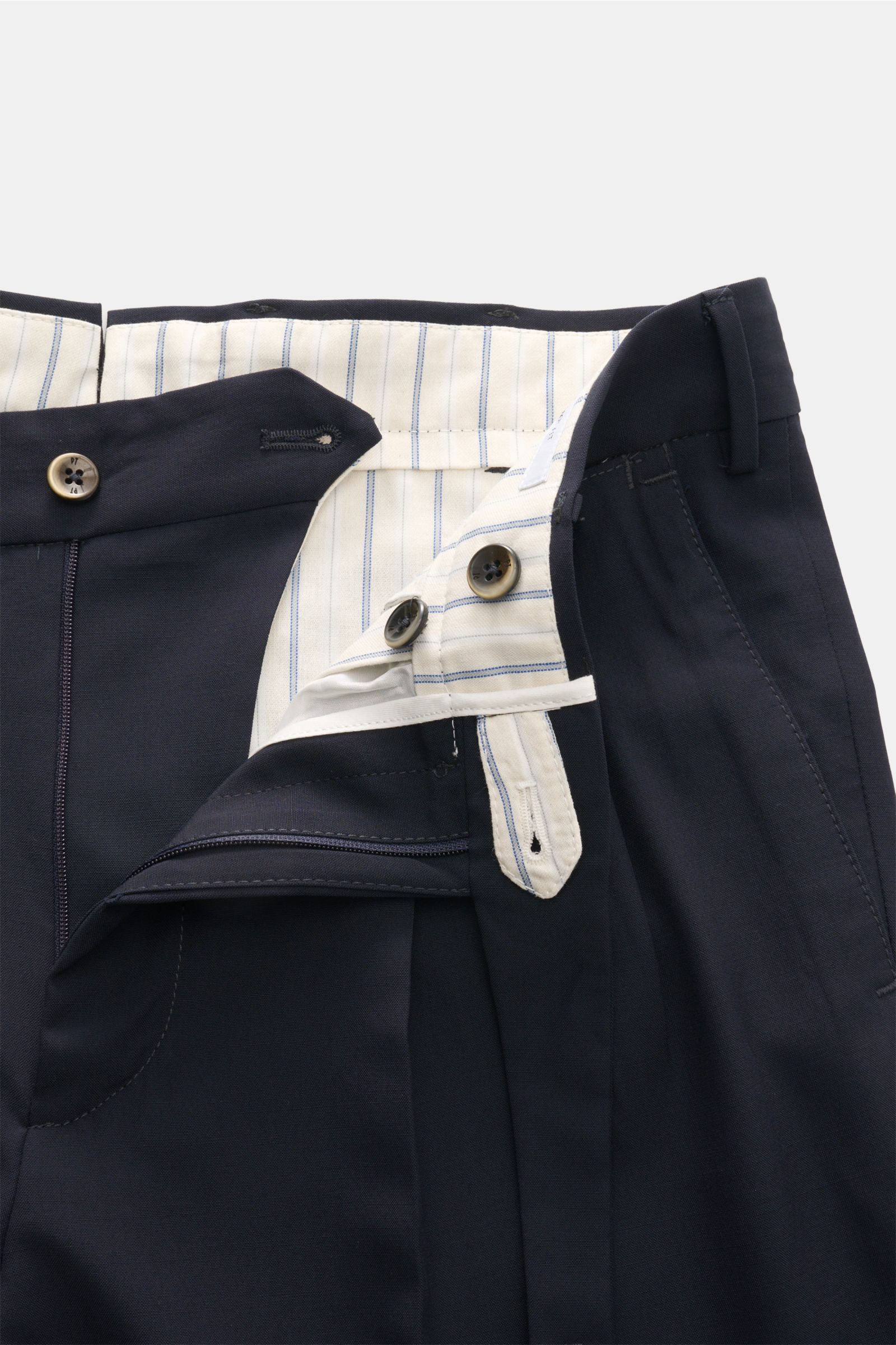 Close-up front view of PT Torino Wool trousers 'Carrot Fit' navy, showing elasticated virgin wool fabric, double pleats, extended buttoned tab, zip, buttons, and striped inner lining for classic elegance with a modern twist. Pure virgin wool, soft feel, c