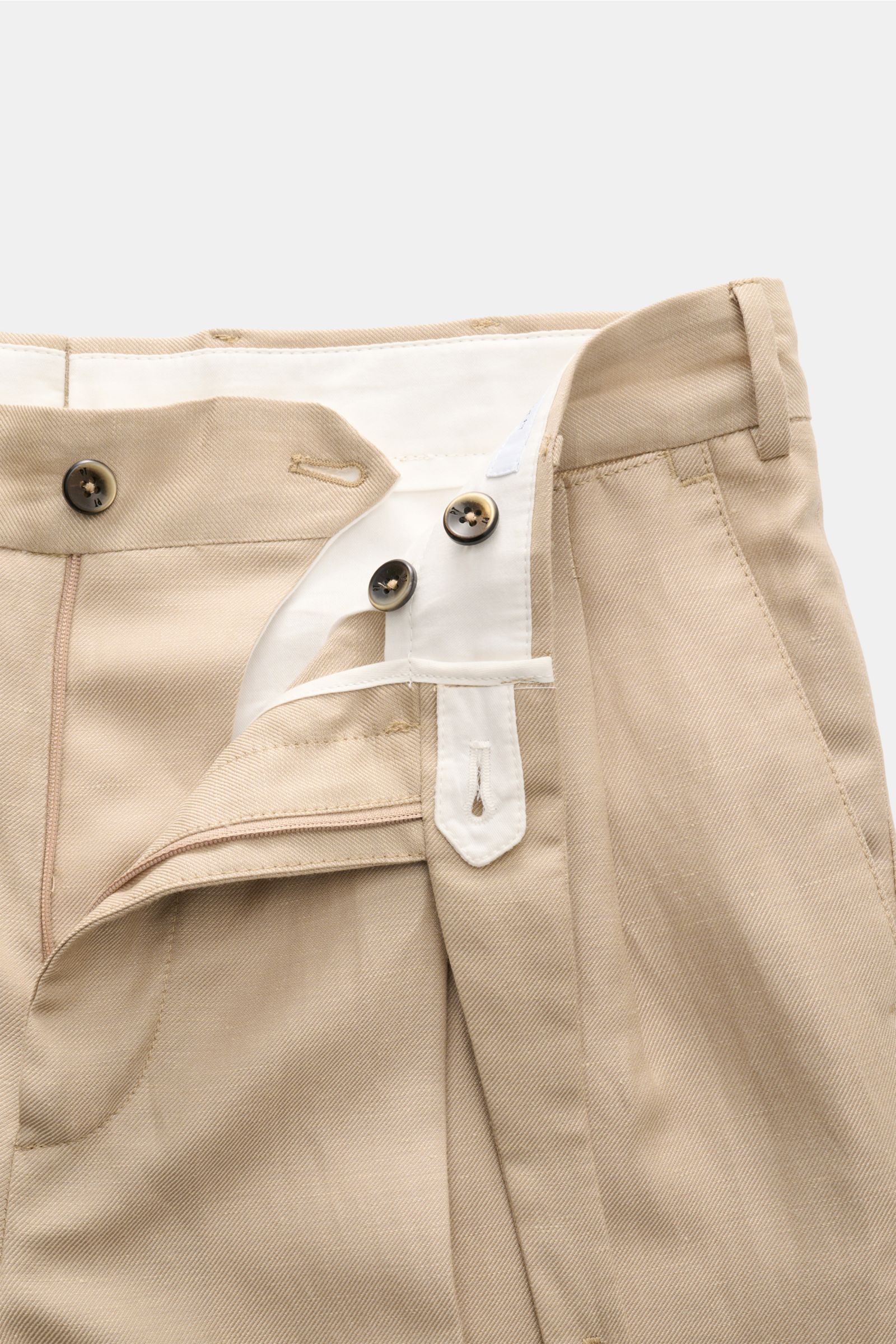 Close-up front view of the beige PT Torino Hose 'Carrot Fit' showing the button fly, waistband, belt loops, and fabric texture with a mix of wool and linen. Italienische Gelassenheit und die Leichtigkeit von Leinen und Schurwolle: Mit dem kurzen Tapered-S