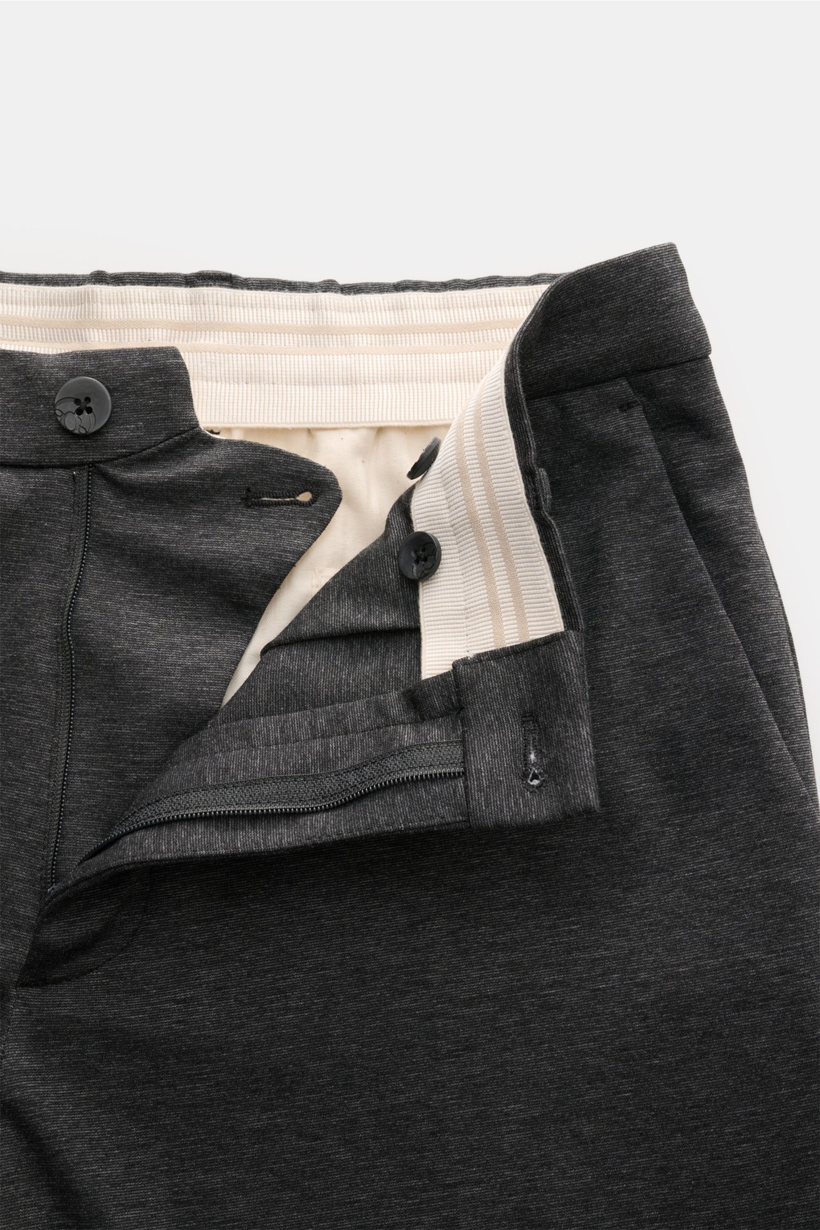 Nahaufnahme der geöffneten Taille der GTA Hose 'Davide' dunkelgrau meliert aus leichtem Baumwoll-Jersey mit Reißverschluss, Bundknopf, innenliegendem elastischem Band und feinem Logo-Detail.