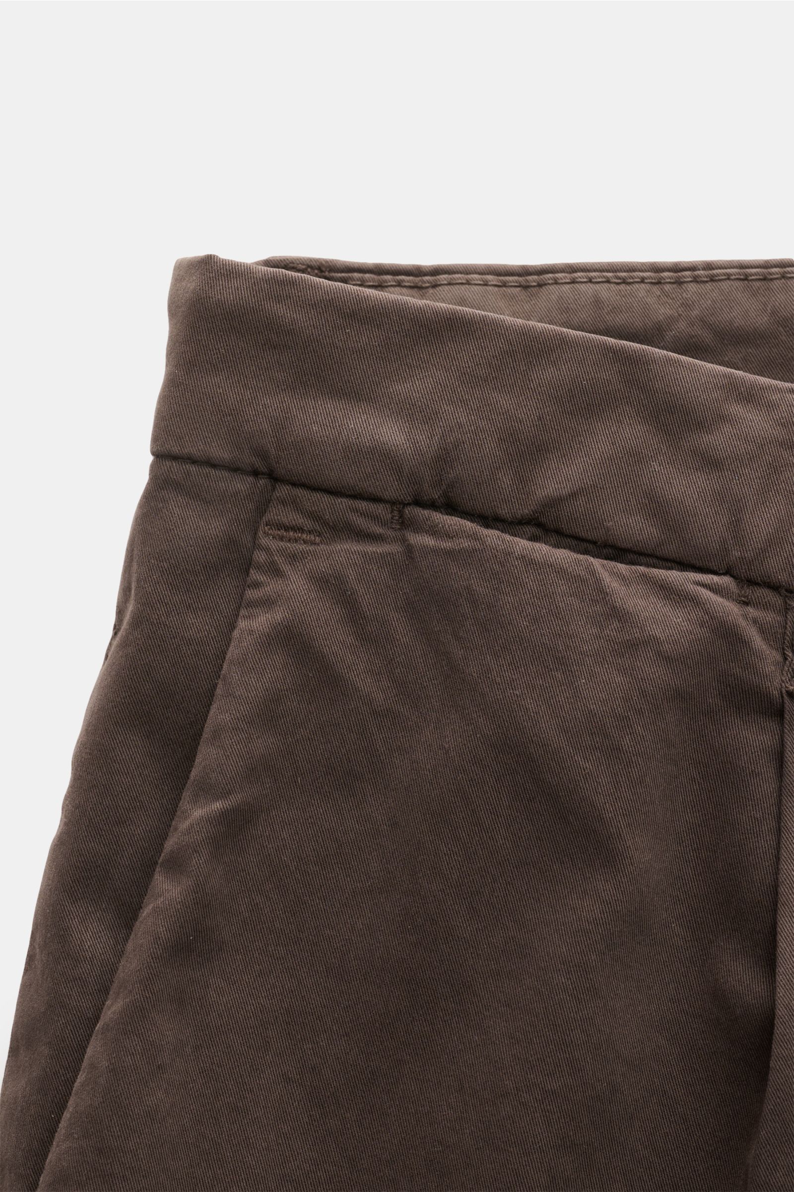 Close-up front view of Briglia 1949 Chinos dark brown made of Tencel and cotton twill with elasticated fabric, zip, button, and French pockets. Maximum comfort meets an elegant silhouette: Summery ease meets timeless aesthetic in these chinos by BRIGLIA 1