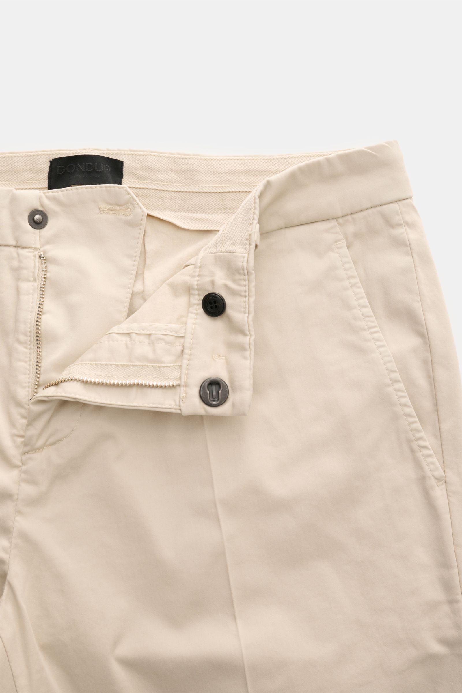 Close-up front view of Dondup Baumwollhose 'Gaubert' sand slim fit cotton pants with zipper, slide button, and French pockets, soft garment dyed fabric, slightly elastic with a typical metal initial.

Description: Für alle Liebhaber von italienischer Mode