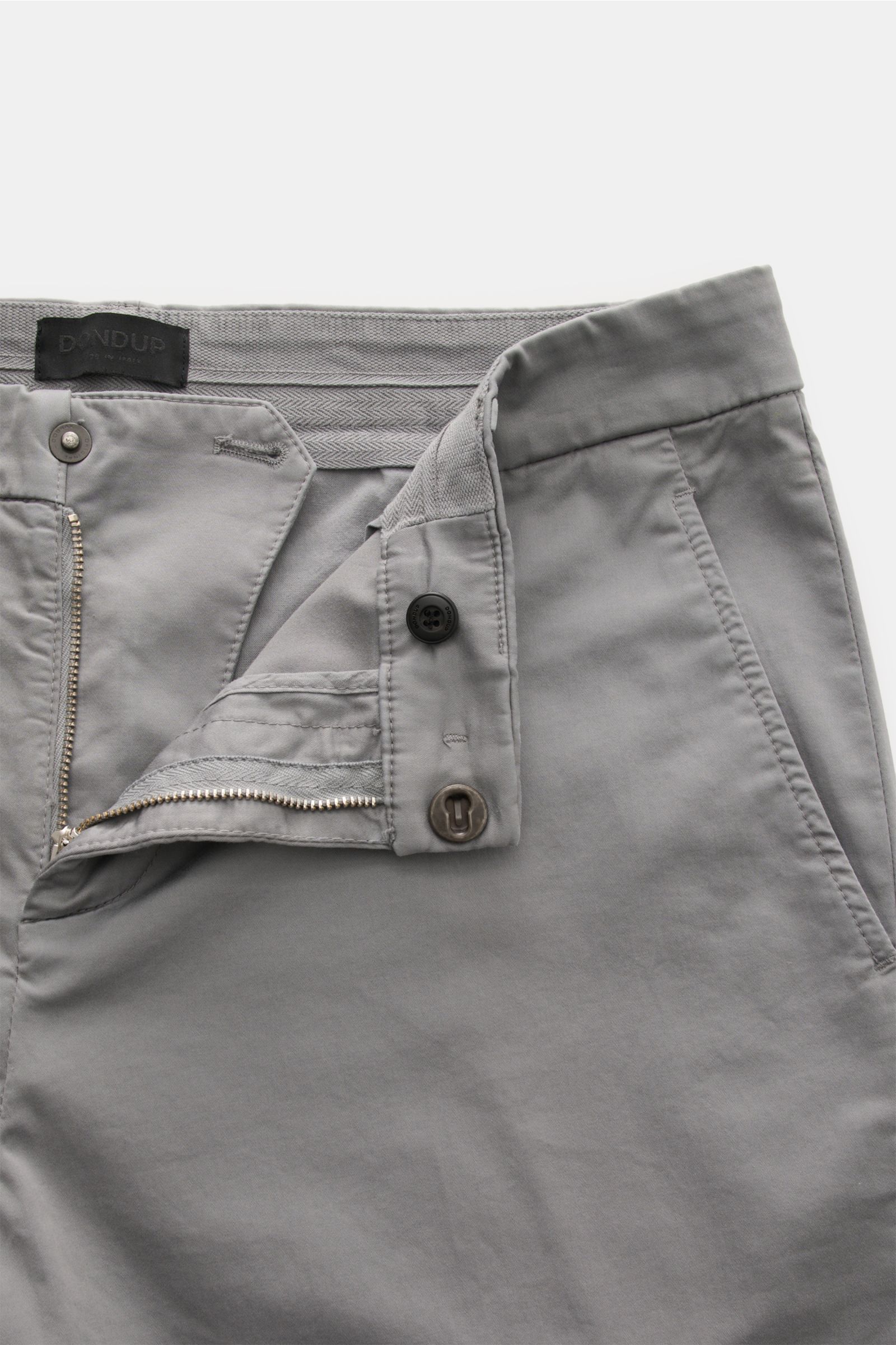 Nahaufnahme der geöffneten Dondup Baumwollhose 'Gaubert' grau aus elastischer, garment dyed Baumwolle mit Slim Fit, Reißverschluss, Slide Button und französischen Taschen.