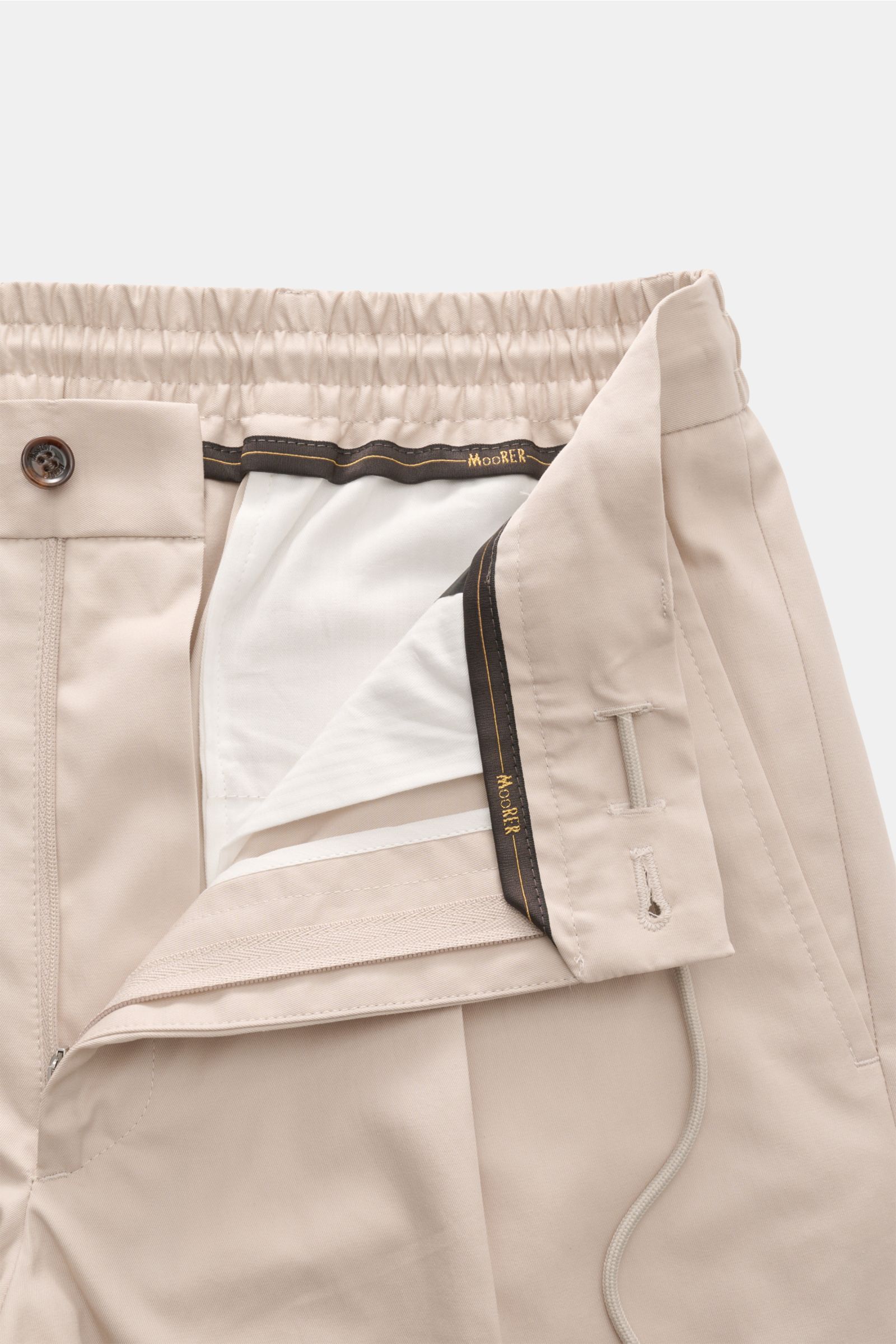 Moorer Jogger pants 'Anton' beige shown from a close-up front perspective, highlighting the zip, button, and partially elasticated waistband with drawstring in lightweight cotton twill fabric. The trousers feature a soft feel, regular fit, slightly tapere