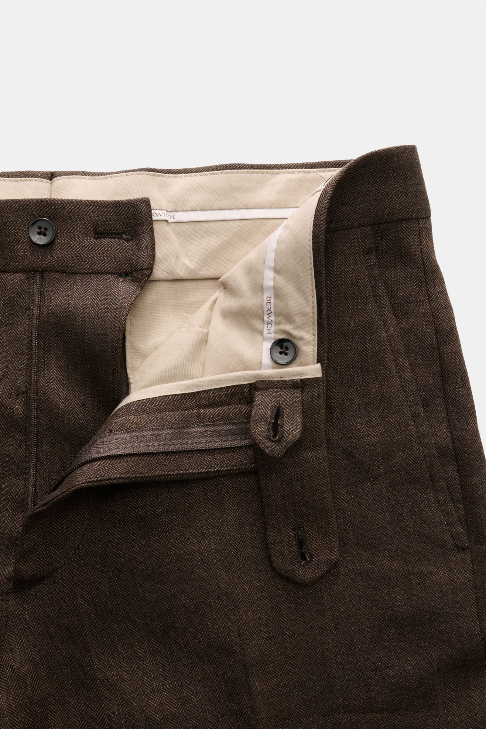 Berwich Leinenhose 'Chiaia' dunkelbraun close-up from above showing waistband, button, zipper, and beige inner lining with herringbone texture. Sommerliche Leichtigkeit verspricht die Hose 'Chiaia' von BERWICH aus reinem Leinen – die materialtypische Hapt