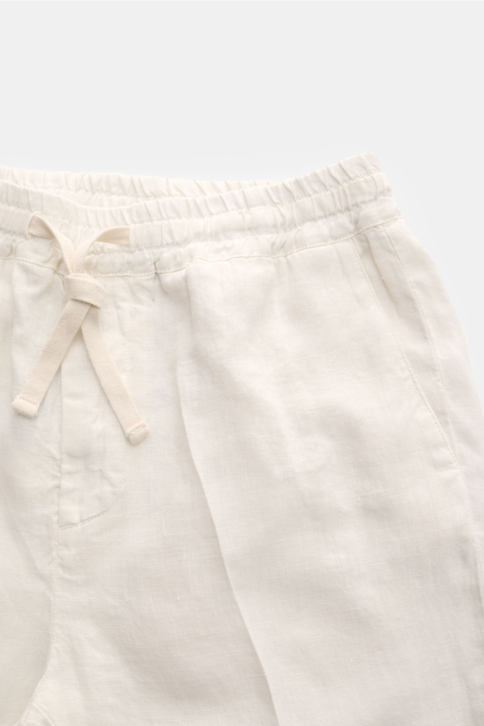 Nahaufnahme der Altea Leinen-Jogpants 'Mattia' offwhite von oben, zeigt elastischen Bund mit Tunnelzug, Eingrifftaschen mit Zipper, weiches reines Leinen, leichter, knöchellanger Tapered Fit, reguläre Oberschenkelweite, französische Taschen und Gesäßtasch