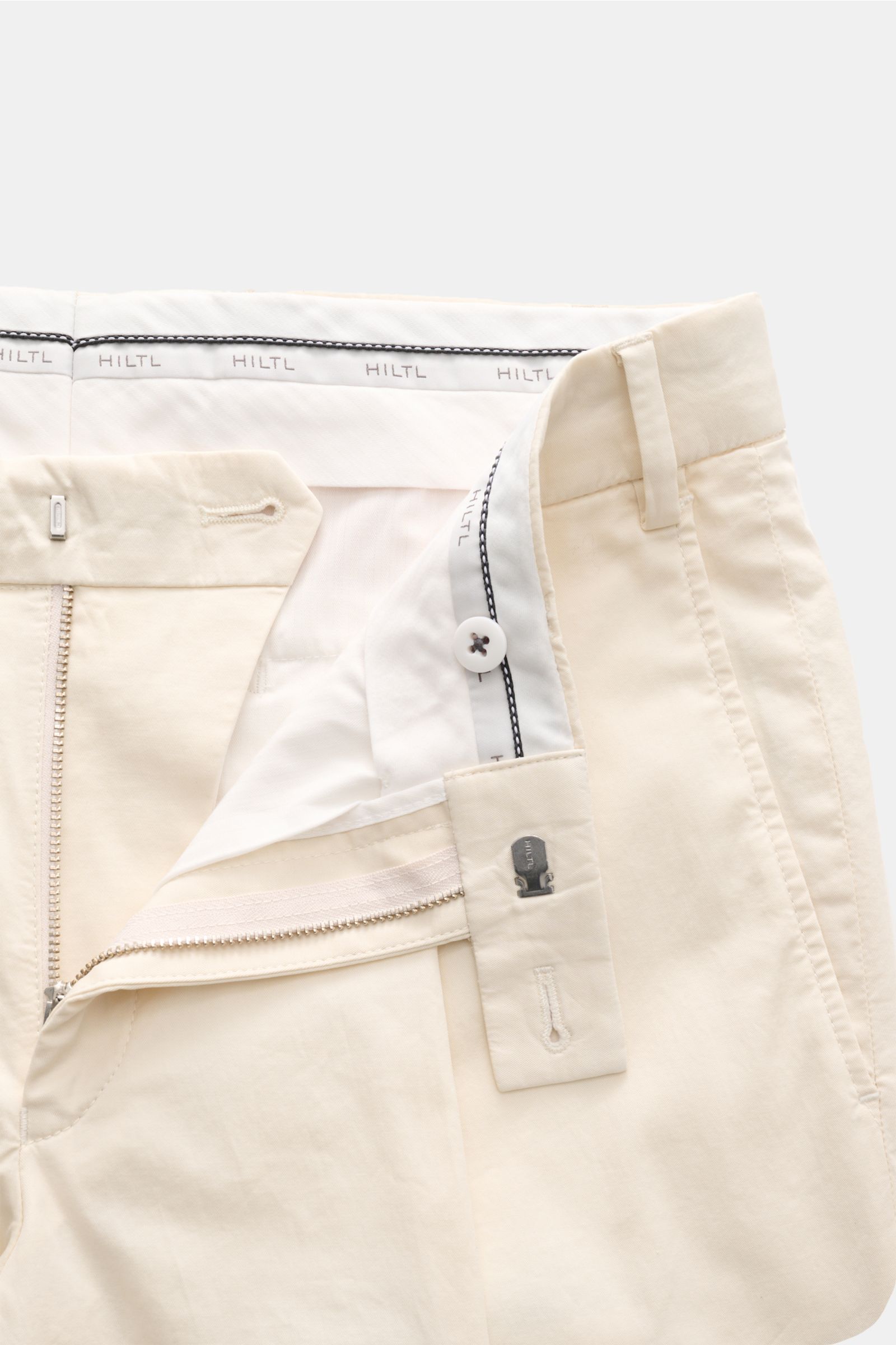 Close-up front view of Hiltl Chino 'Primo' creme with zipper, button, twill cotton, elastic, soft grip, regular fit, slight taper.  

Description: Vielseitiges Essential: Die Chino 'Primo' von HILTL im überzeugt mit ihrer klaren Silhouette und lässt si