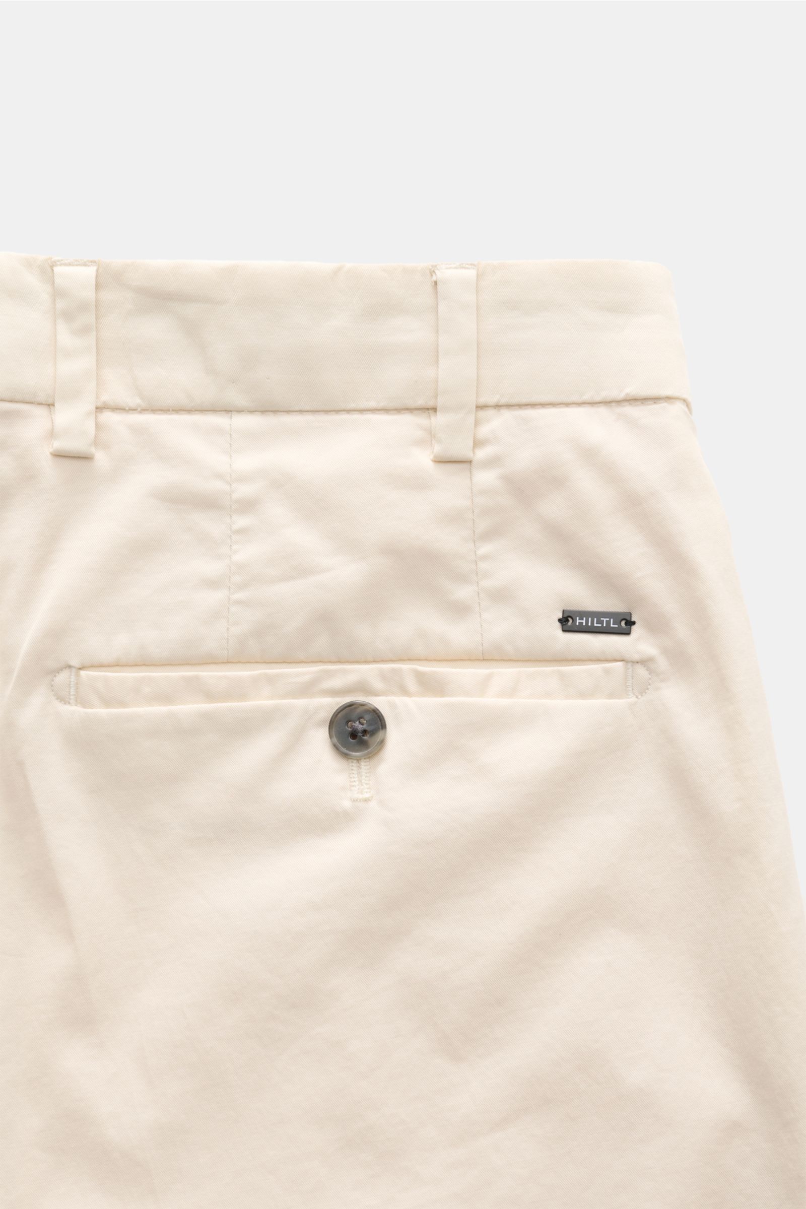 Hiltl Chino 'Primo' creme shown from the back upper section, featuring twill cotton, elastic quality, soft touch, regular fit, slightly tapered, zipper and button, simple pleat, French pockets, and buttoned back pocket. Vielseitiges Essential: Die Chino '