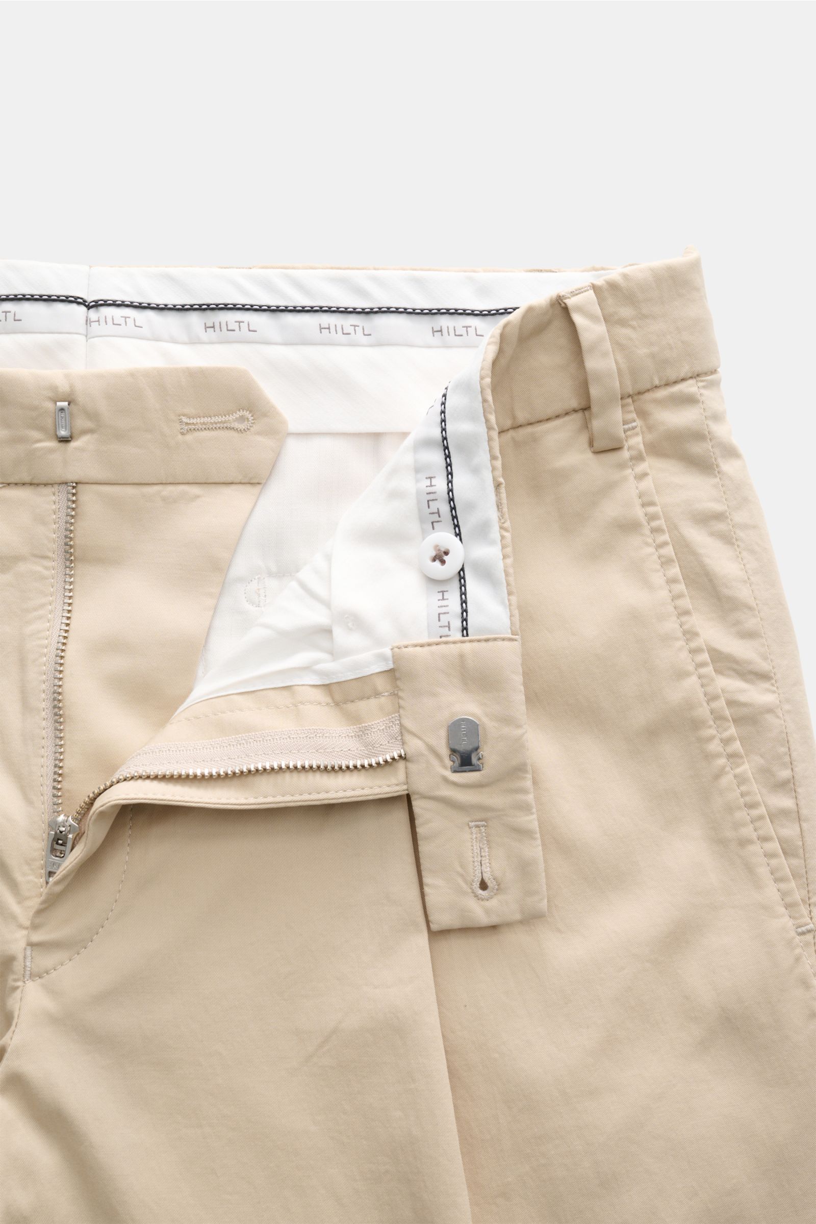 Close-up front view of Hiltl Chino 'Primo' sand pants showing zipper, button, and belt loop details in soft cotton twill fabric.

Description: Vielseitiges Essential: Die Chino 'Primo' von HILTL im überzeugt mit ihrer klaren Silhouette und lässt sich m
