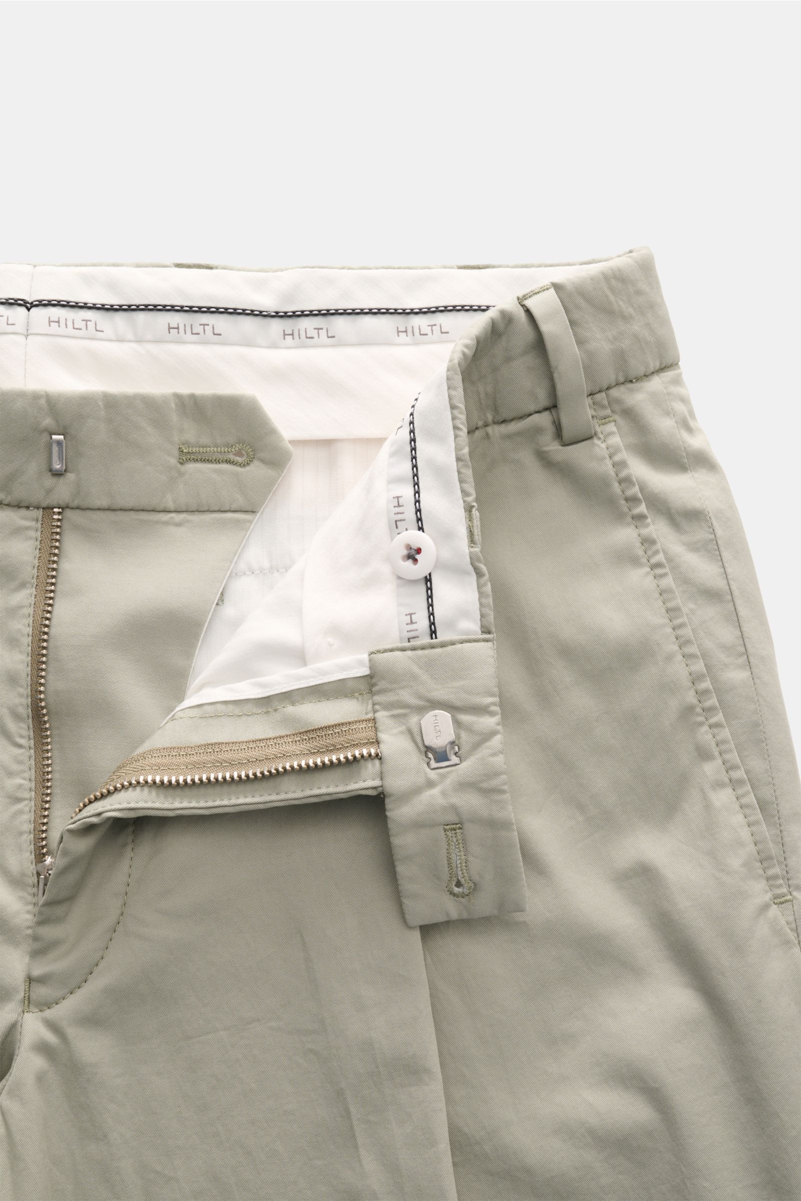 Hiltl Chino 'Primo' salbei, Nahaufnahme von Bund und offenem Reißverschluss, Baumwoll-Twill, elastisch, Regular Fit, französische Taschen.