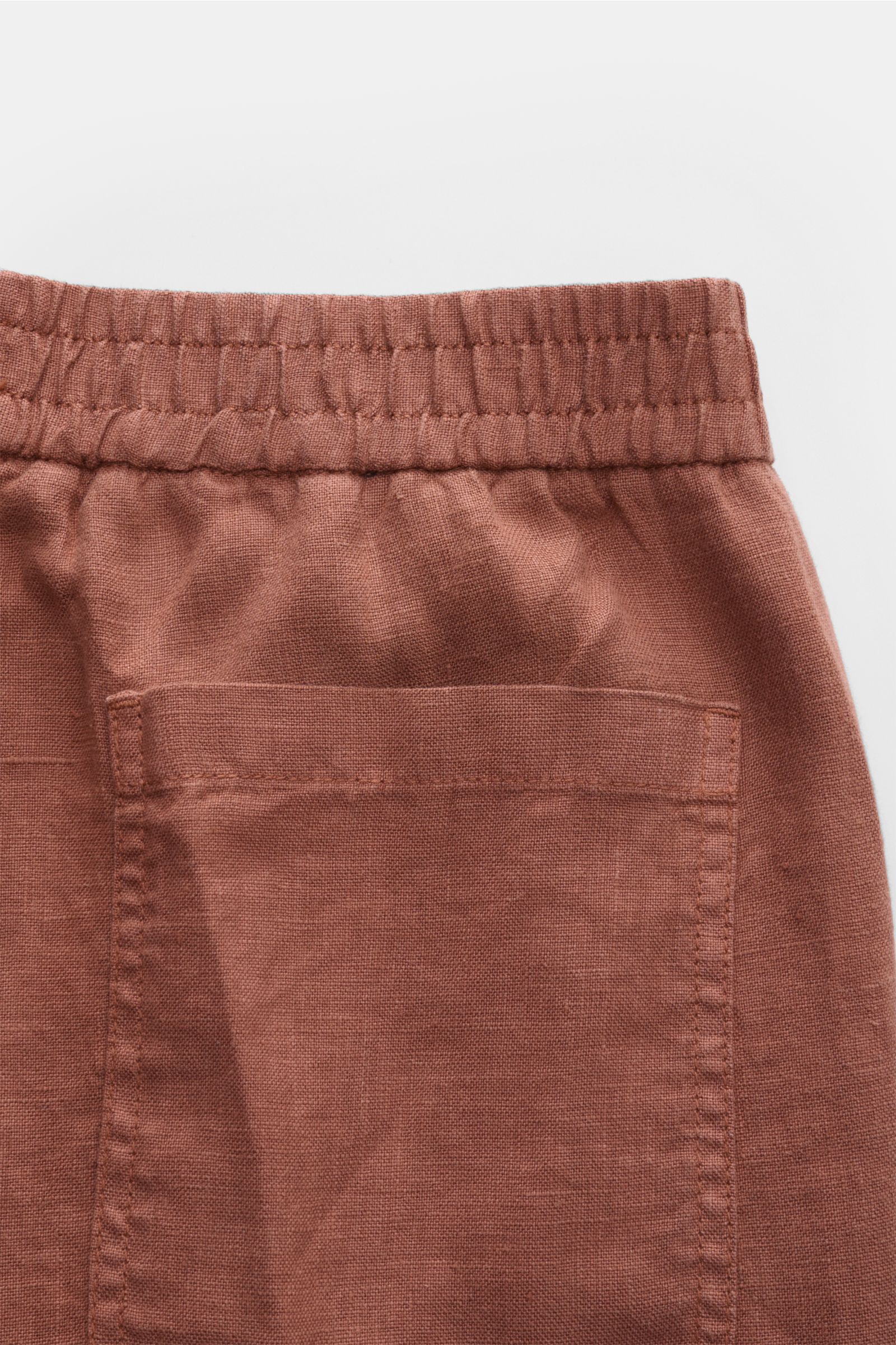 04651/ A trip in a bag Leinen-Jogpants 'Linen Pants' rostbraun mit elastischem Bund, aufgesetzter Gesäßtasche, typischer Leinenstruktur, Detailaufnahme von hinten.