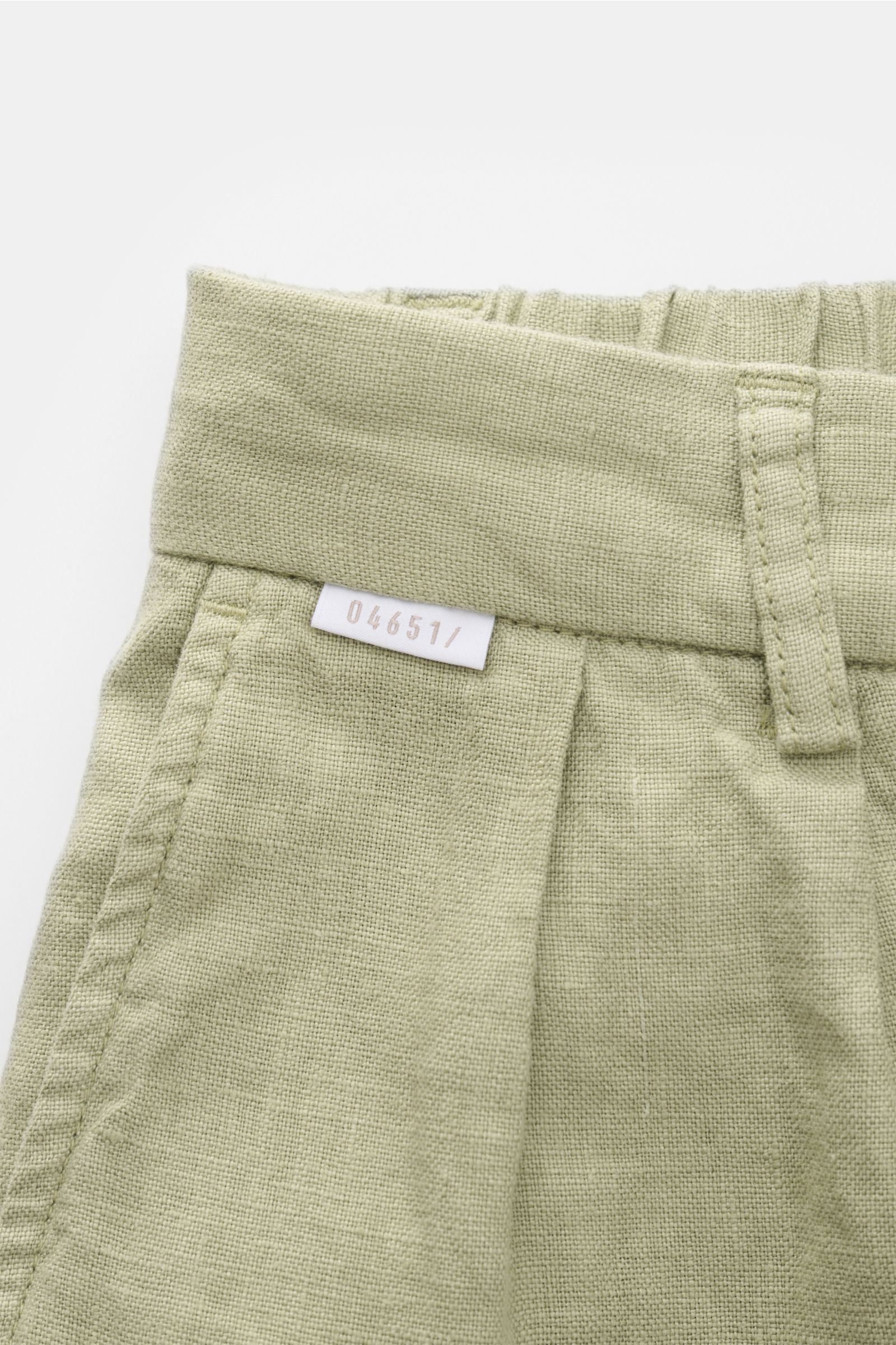 Nahaufnahme der Bundpartie der 04651/ A trip in a bag Leinen-Jogpants 'Linen Pants' salbei, reines Leinen, Regular Fit, schmal zulaufend, mit kleinem Weblabel.