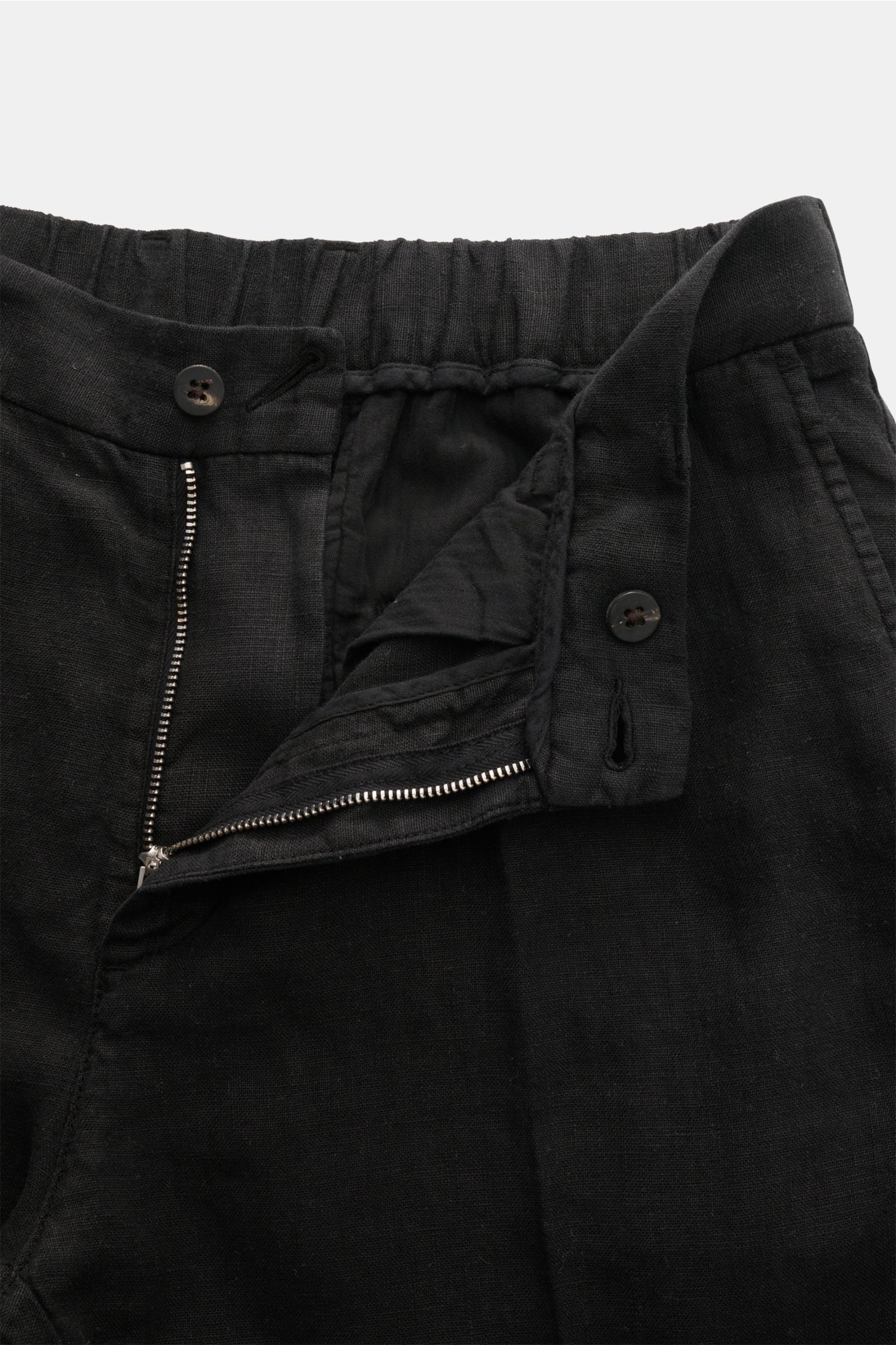 Close-up front view of 04651/ A trip in a bag Linen jogger pants 'Linen Pants' black showing zip, button, and partially elasticated waistband with drawstring. Perfect for warm days: These linen jogger pants by 04651/ A TRIP IN A BAG are the ideal summer e