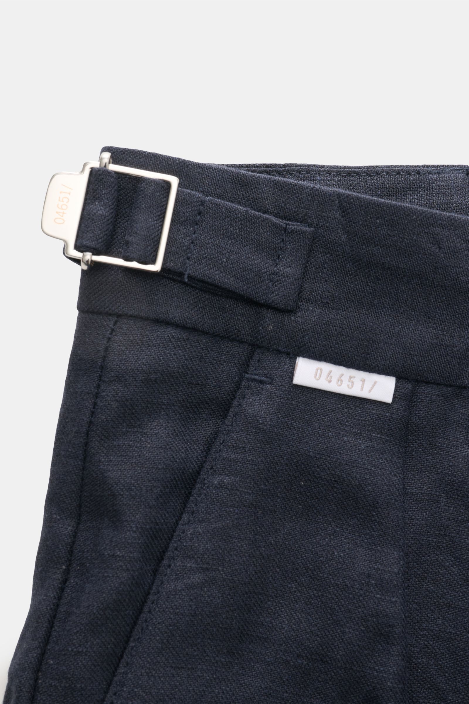 Nahaufnahme der Taille der 04651/ A trip in a bag Leinenhose navy mit Side Adjuster, feiner Leinenstruktur und kleinem Weblabel, seitlich fotografiert.