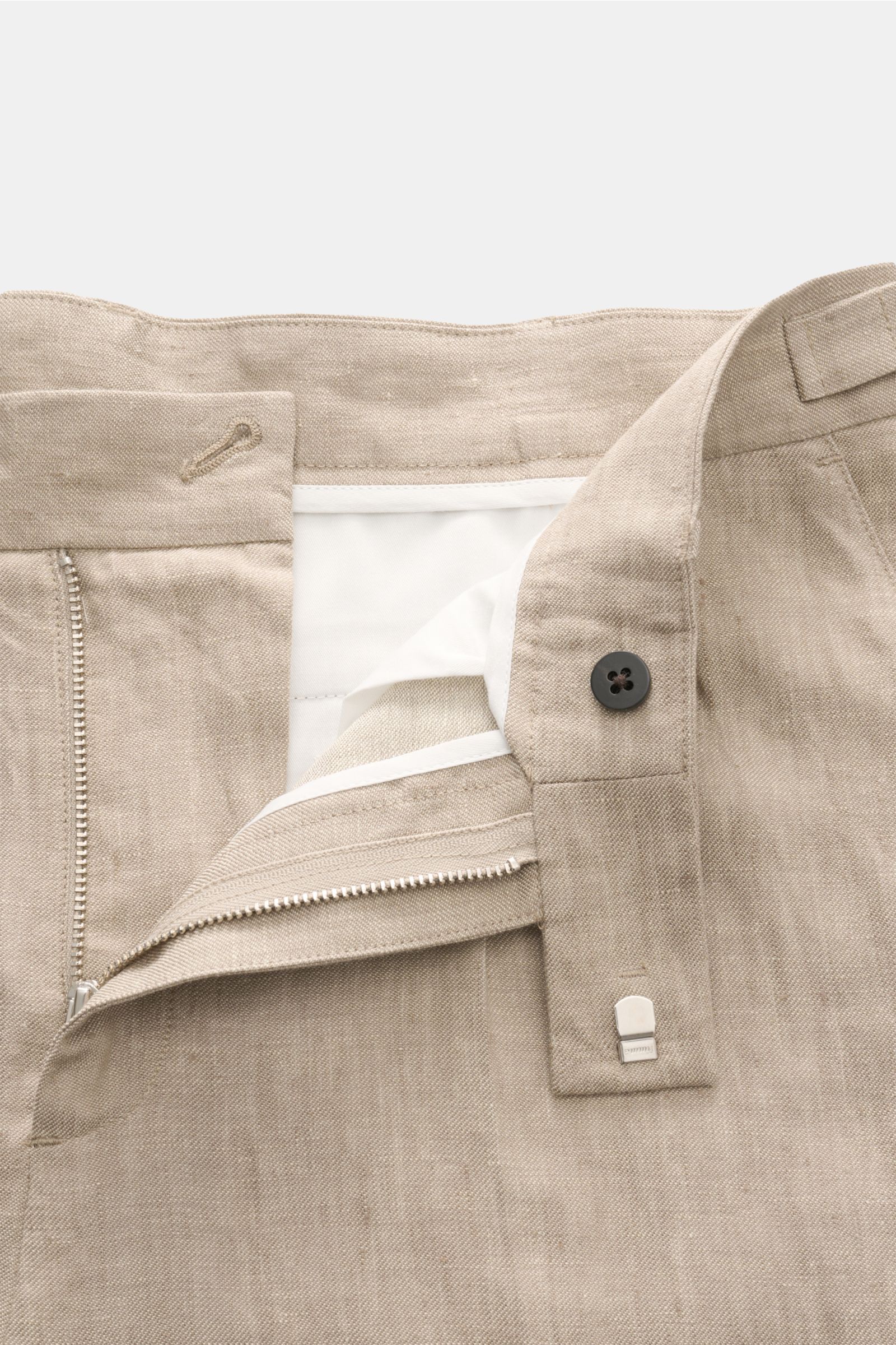 Close-up der geöffneten Bund- und Reißverschlusspartie der 04651/ A trip in a bag Leinenhose taupe meliert aus reinem Leinen, Tapered Fit.