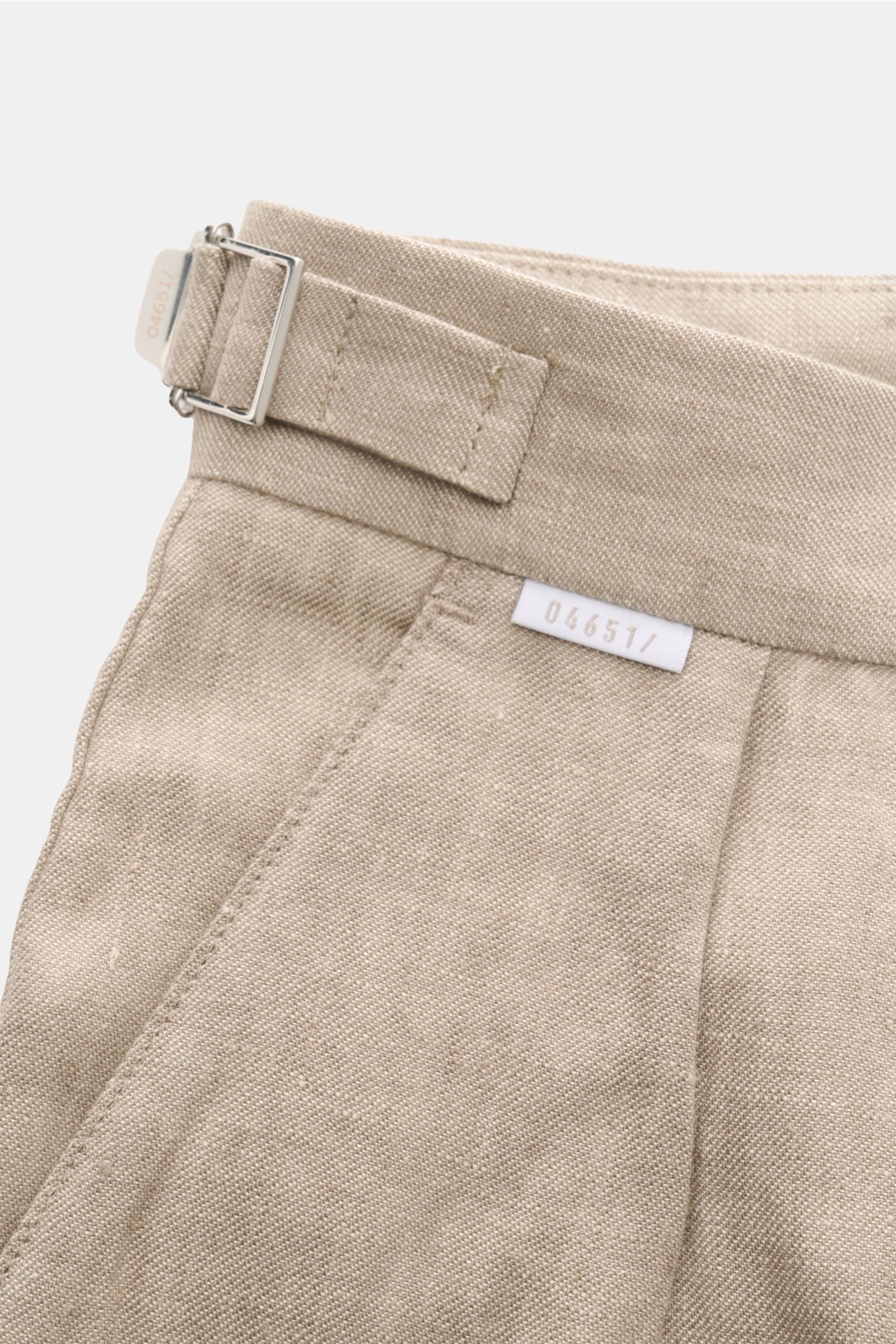 Nahaufnahme des Bunds der 04651/ A trip in a bag Leinenhose taupe meliert aus reiner Leinenqualität mit Side Adjuster, Bundfalte und Weblabel.