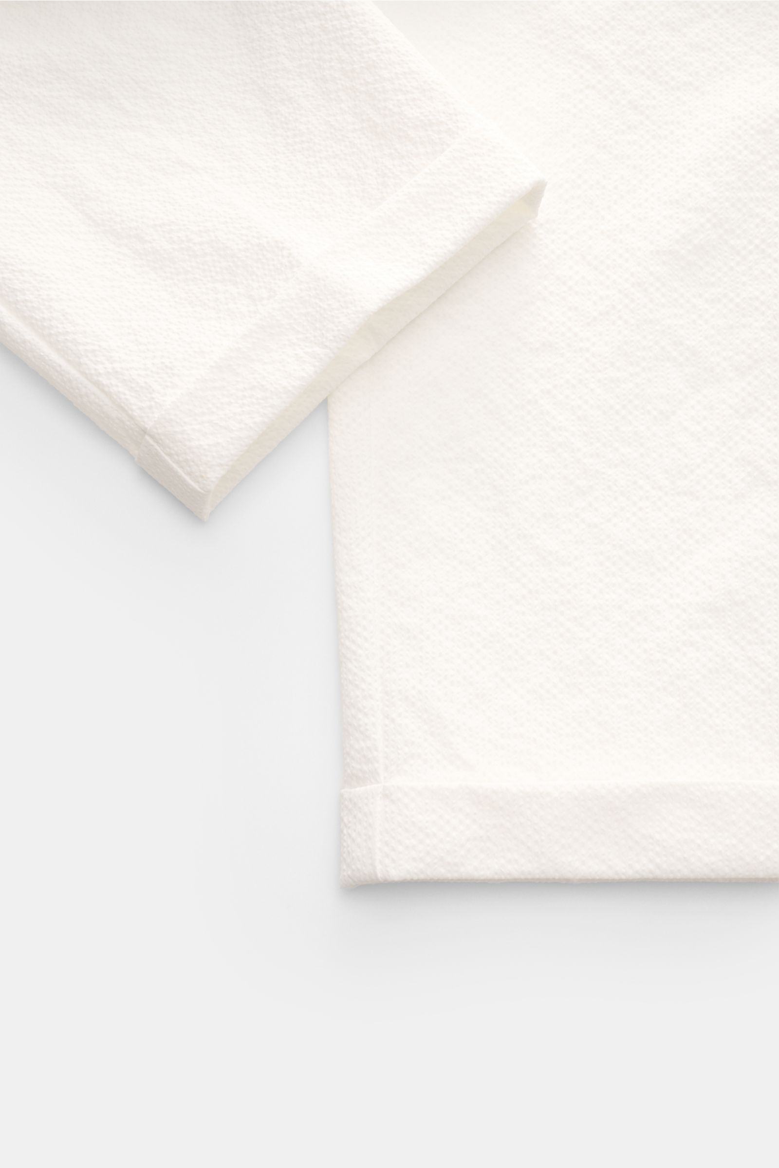 Nahe Aufnahme von Saum und Beinabschluss der 04651/ A trip in a bag Seersucker-Hose 'Technical Seersucker' offwhite aus Microfaser mit feiner Struktur, griffiger Qualität, fixiertem Saumaufschlag und materialtypischem Seersucker-Twill.