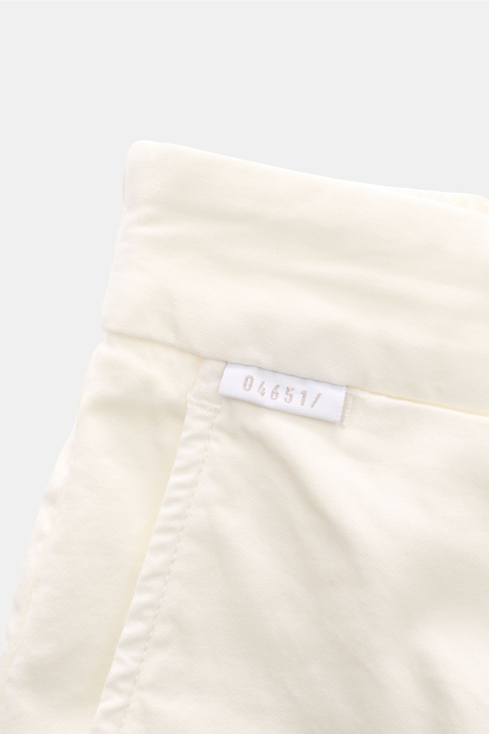 Close-up top-down view of 04651/ A trip in a bag Cotton jogger pants 'Flex Light' cream, showing elasticated waistband and label. Get a smart-casual look for warm days: The cotton jogger pants by 04651/ A TRIP IN A BAG combine smart chinos style with a re