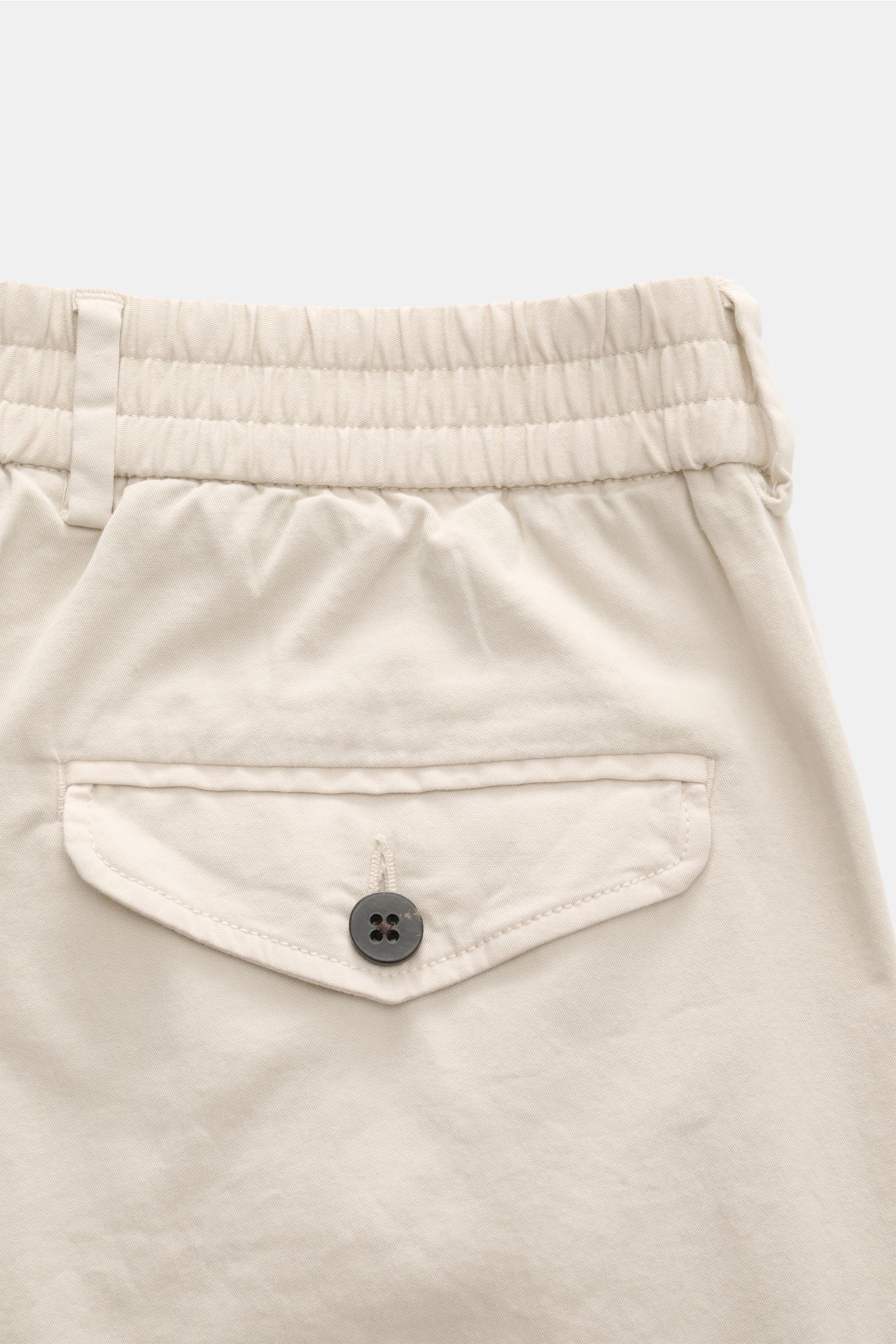 Detailaufnahme der Rückseite der beige 04651/ A trip in a bag Baumwoll-Jogpants 'Flex Light' mit elastischem Bund, geknöpfter Gesäßtasche und weichem Griff.