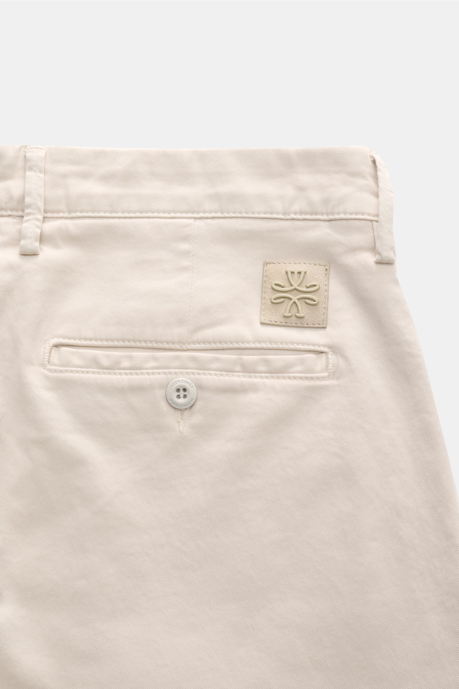 Rear close-up view of Jacob Cohen Chino 'Bobby' sand, slim fit pants made of pure elastic cotton with soft touch, featuring French pockets, buttoned back pocket, tonal suede leather patch, zipper and waistband button.

Setzen Sie auf modernen Luxus im All