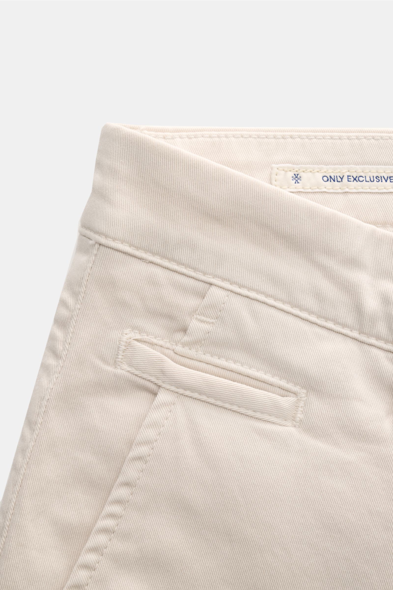Close-up front-side view of Jacob Cohen Chino 'Bobby' sand, slim fit in elastic, pure cotton with soft touch, featuring French pockets, coin pocket, buttoned back pockets, zipper, waistband button, and tonal velour leather patch. Setzen Sie auf modernen L