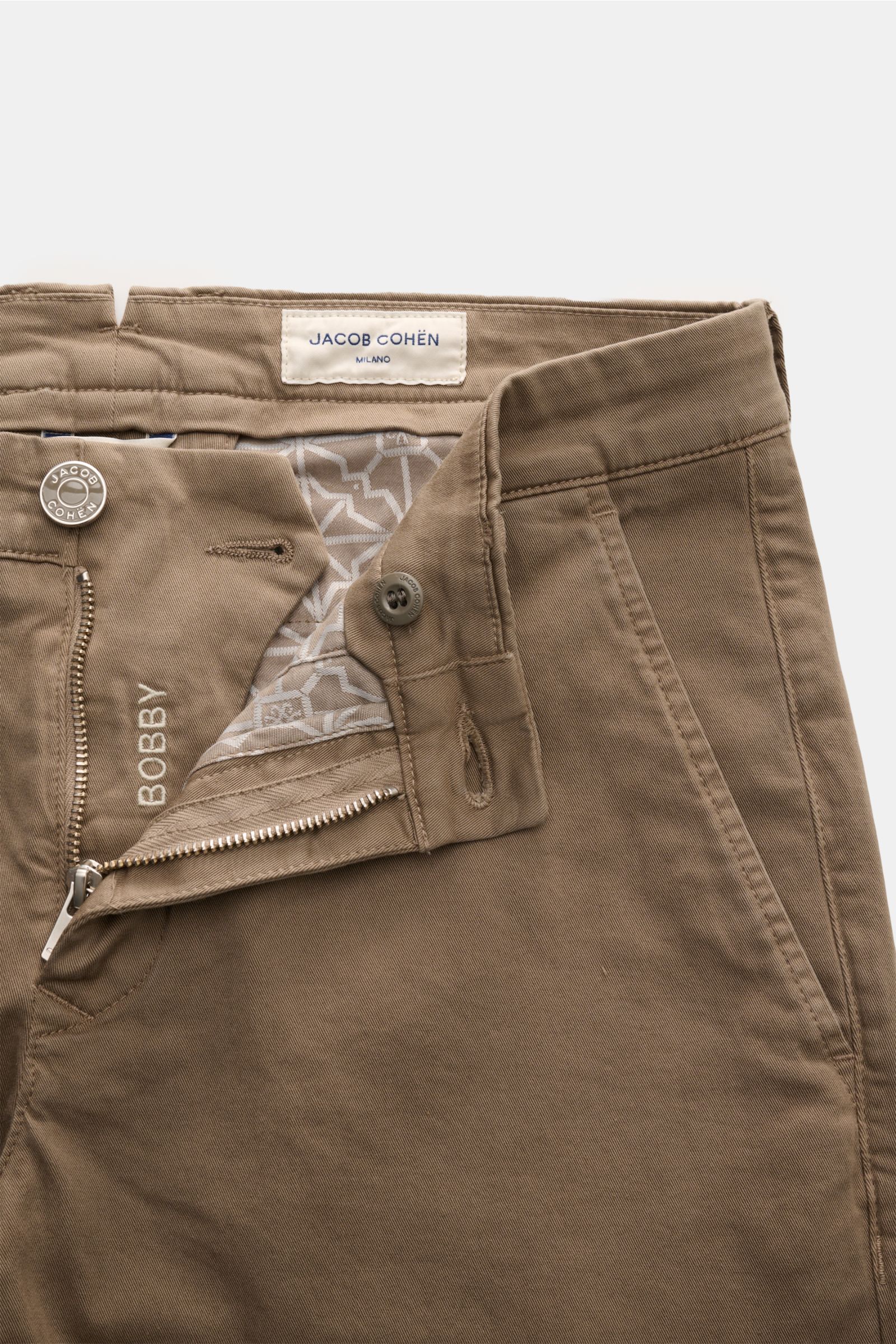 Close-up front view of the Jacob Cohen Chino 'Bobby' graubraun in slim fit, made of elastic pure cotton with soft touch, featuring zipper and button, French pockets, coin pocket, back pockets with buttons, and tonal velvet leather patch, showcasing modern