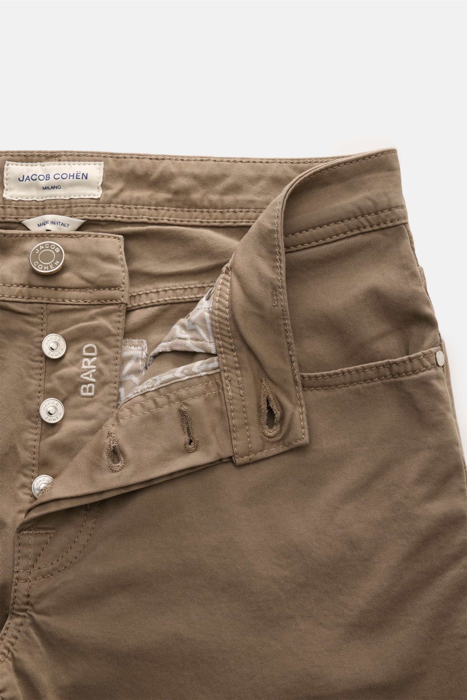 Close-up front view of Jacob Cohen Baumwollhose 'Bard' graubraun with button fly, tonal stitching, and Leather Patch in Ponyfell-Optik, made of soft elastic pure cotton.

Description: Setzen Sie auf modernen Luxus im Alltag: Die Five-Pocket-Hose 'Bard'