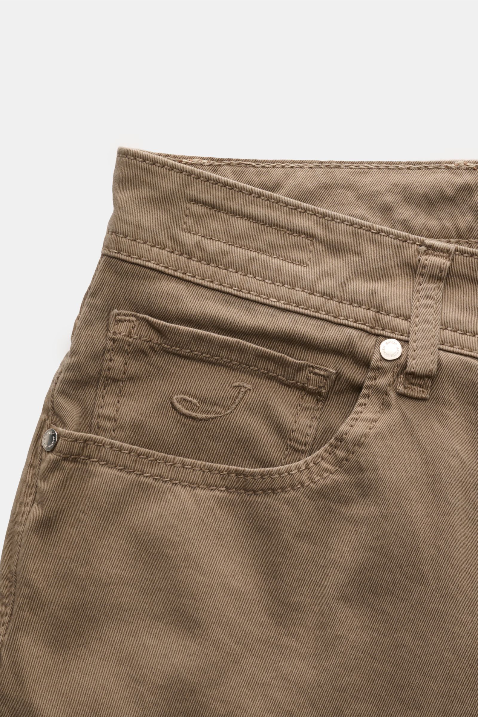 Close-up front view of Jacob Cohen Baumwollhose 'Bard' graubraun in slim fit, elastic pure cotton with five-pocket style, tonal stitching, and pony hair leather patch. Setzen Sie auf modernen Luxus im Alltag: Die Five-Pocket-Hose 'Bard' von JACOB COHEN ko