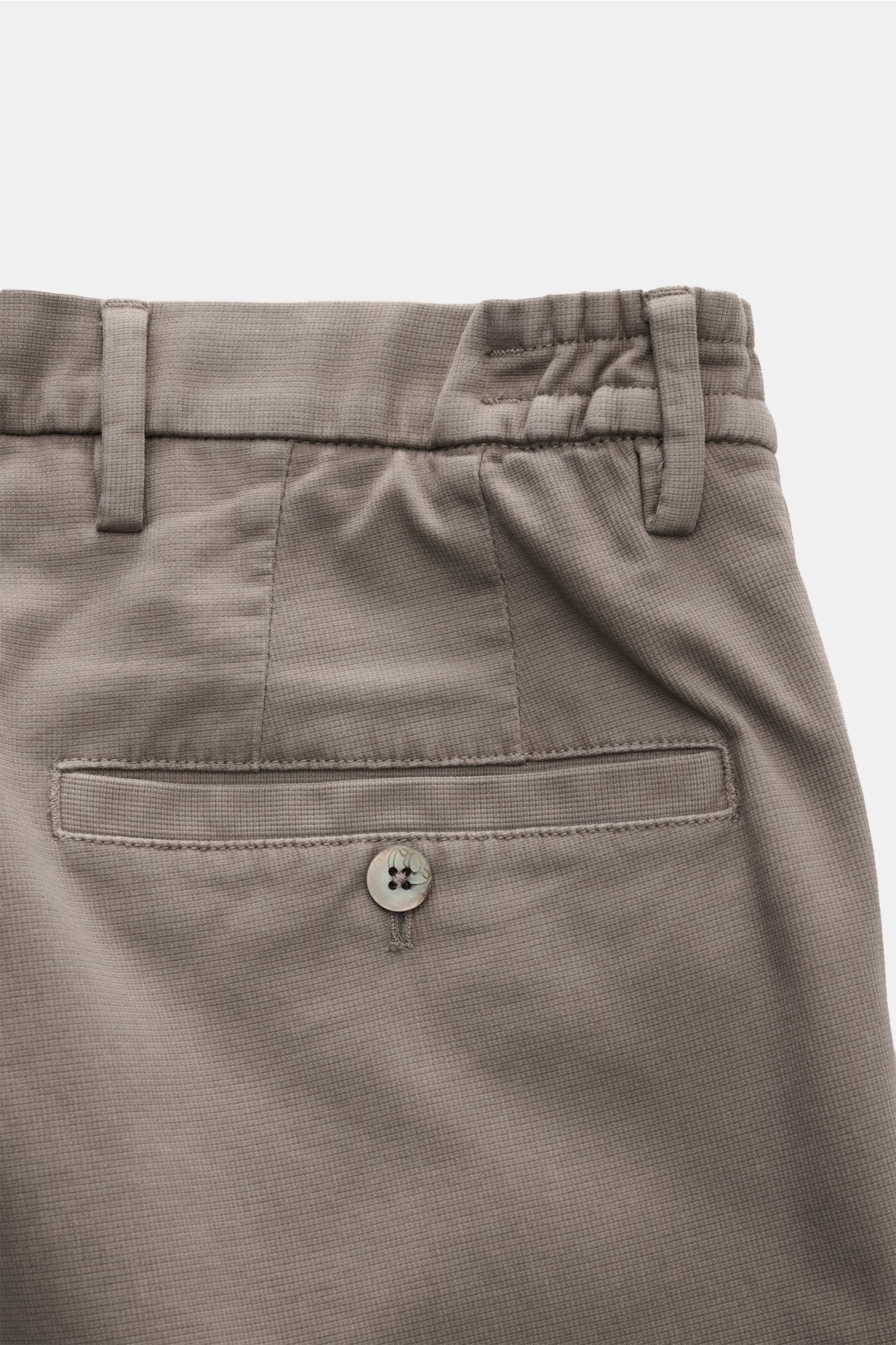 Close-up rear view of GTA Trousers 'Dennis' grey-brown showing back pocket with button, belt loops, and elasticated waistband.

Description: With the cropped, tapered trousers 'Dennis', GTA presents an essential that combines the relaxed feel of the in