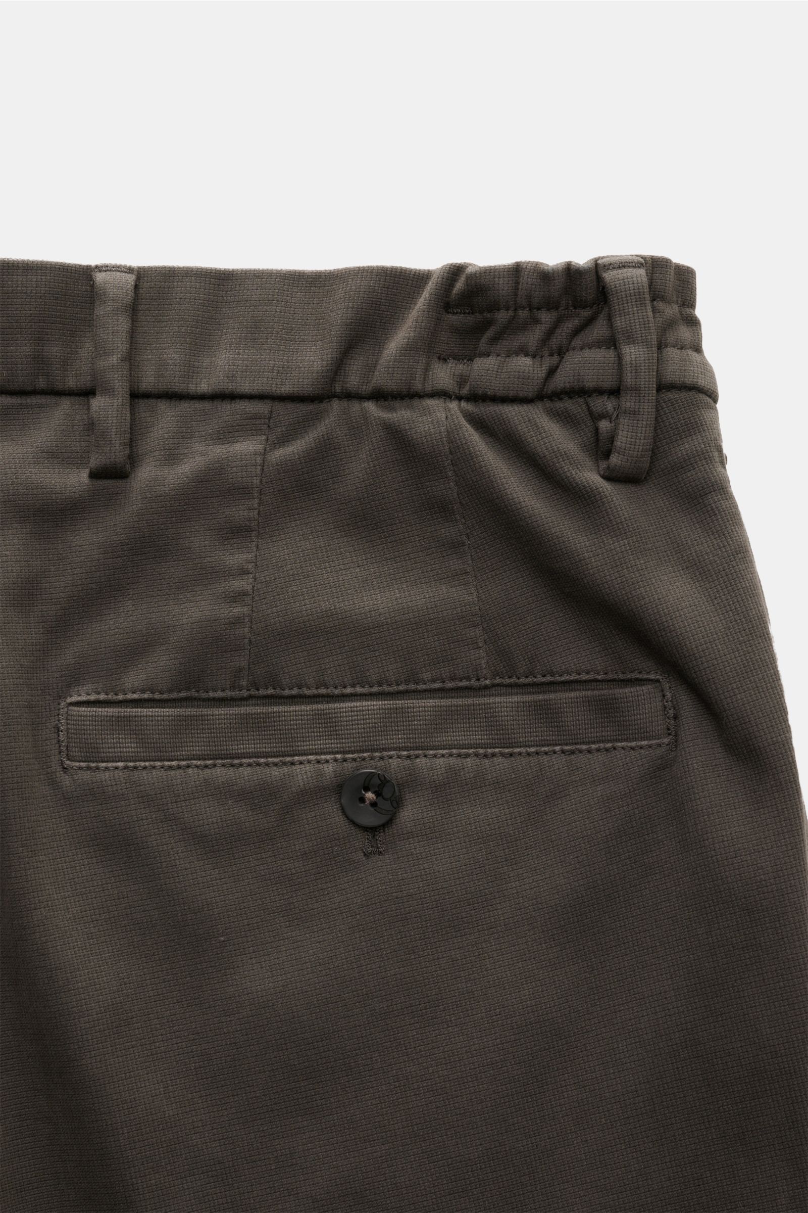 Close-up rear view of the GTA Trousers 'Dennis' dark grey, showing the back pocket with button, elasticated waistband, and fabric texture. With the cropped, tapered trousers 'Dennis', GTA presents an essential that combines the relaxed feel of the interna