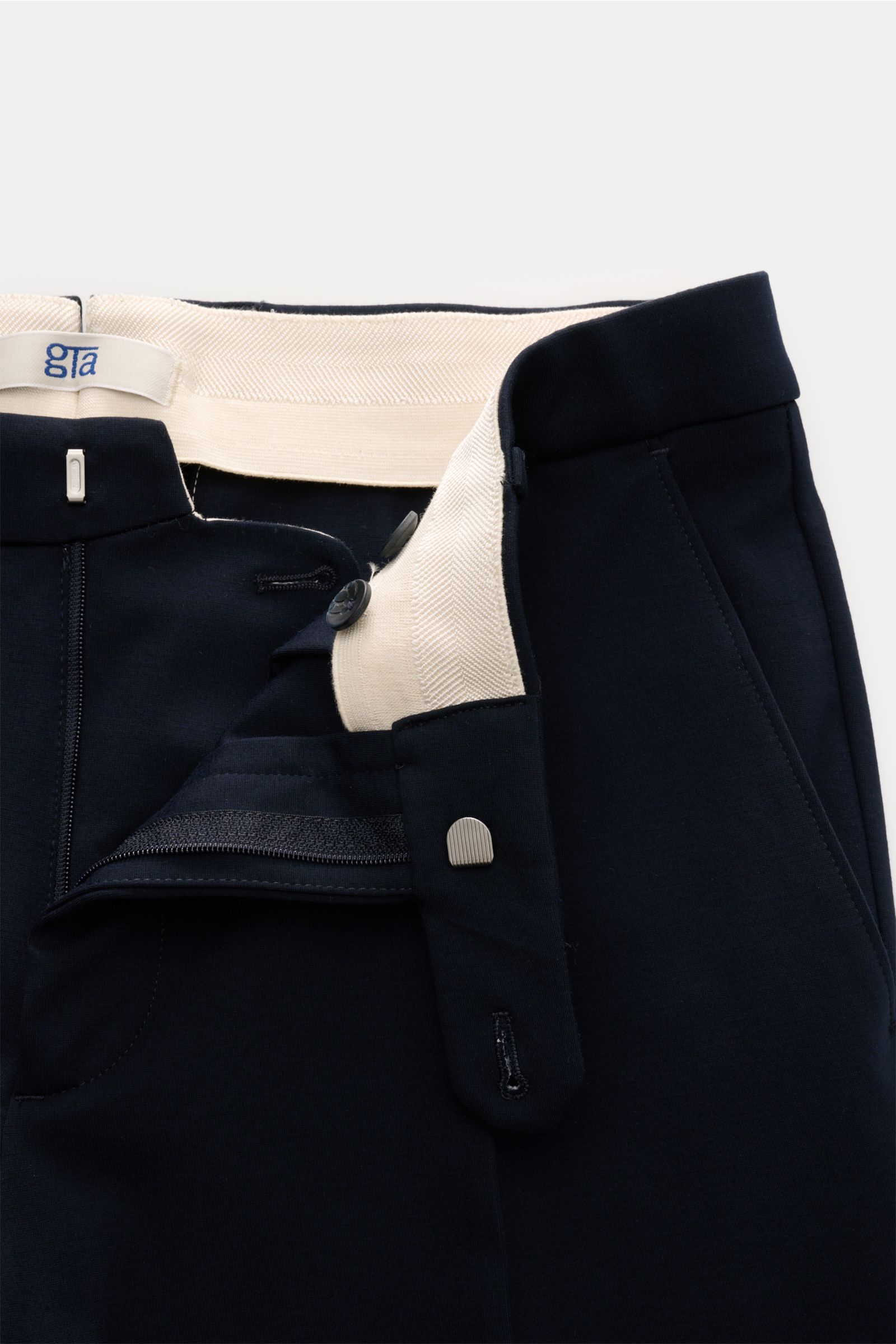 Close-up front view of navy GTA Trousers 'Federico' showing zipper, button, waistband with elastic insert, and pocket details, for stylish office looks: The trousers 'Federico' by GTA combine maximum comfort with timeless elegance to make a versatile esse