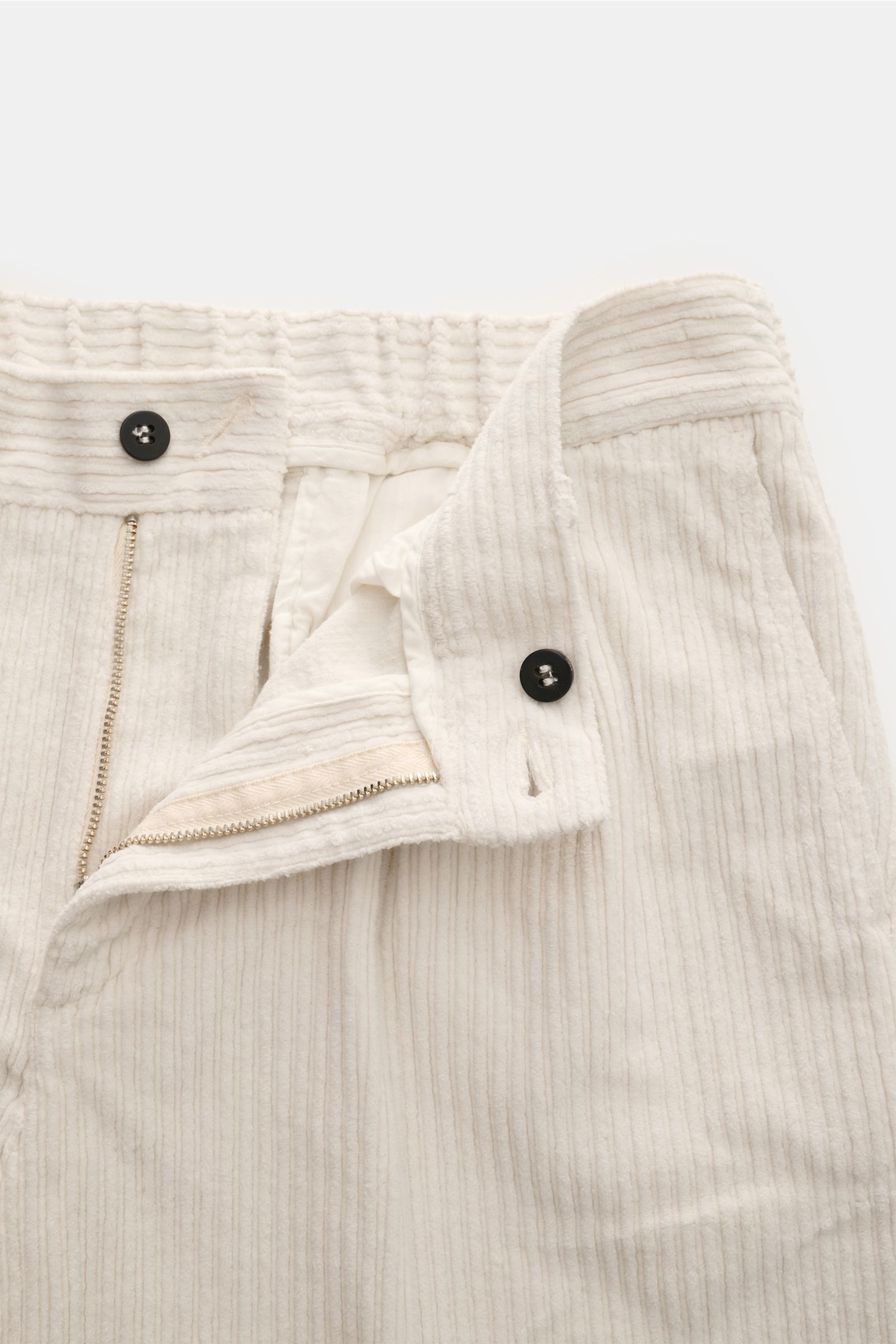 Frontansicht der geöffneten 04651/ A trip in a bag Cordhose offwhite mit Reißverschluss, Bundknopf, elastischer Baumwolle und feiner Cordstruktur.