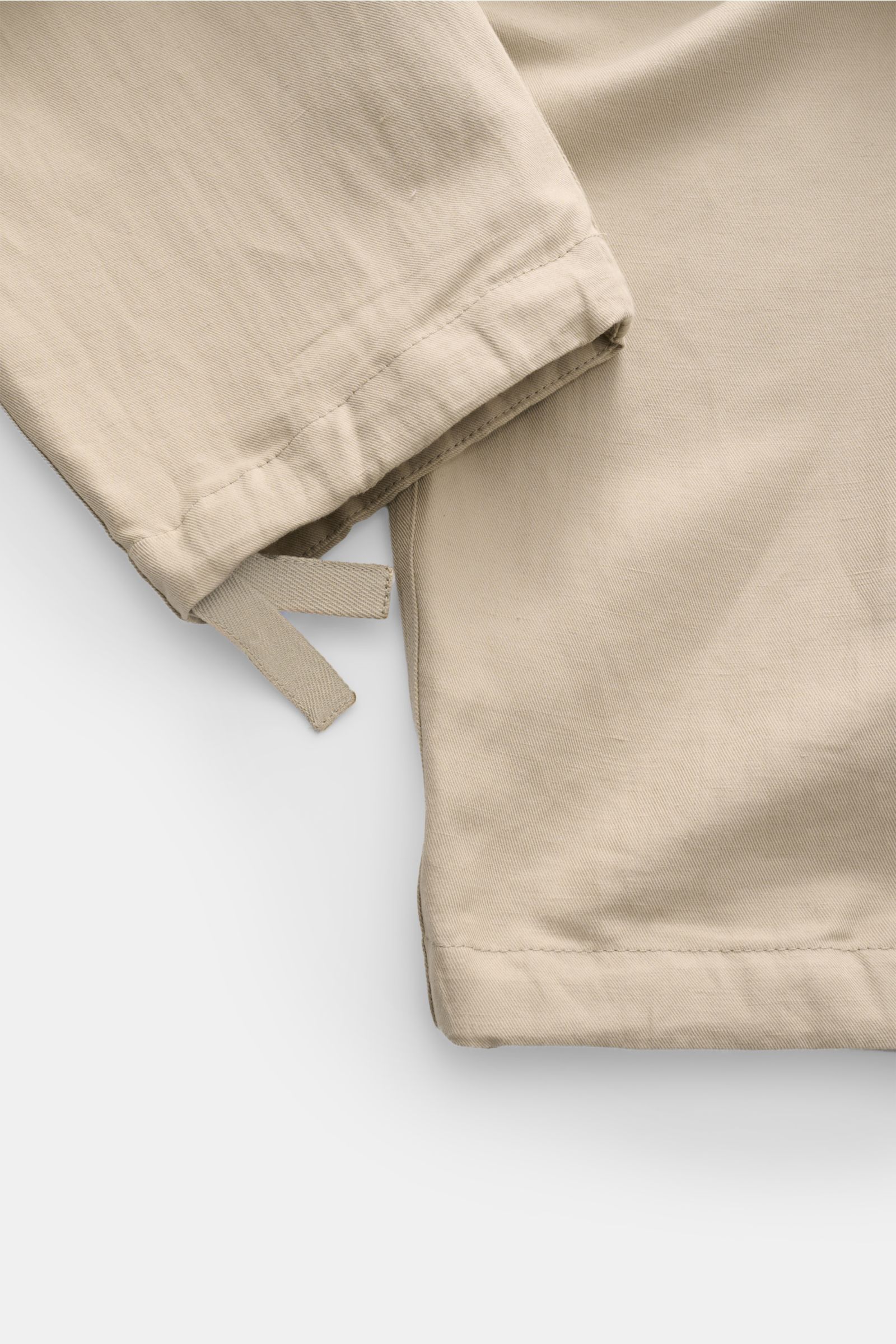 Beige Brunello Cucinelli Jogpants aus Twill mit weichem Griff, knöchellang, geradem Schnitt, Button Fly, Detailaufnahme vom Saum, schräg fotografiert.