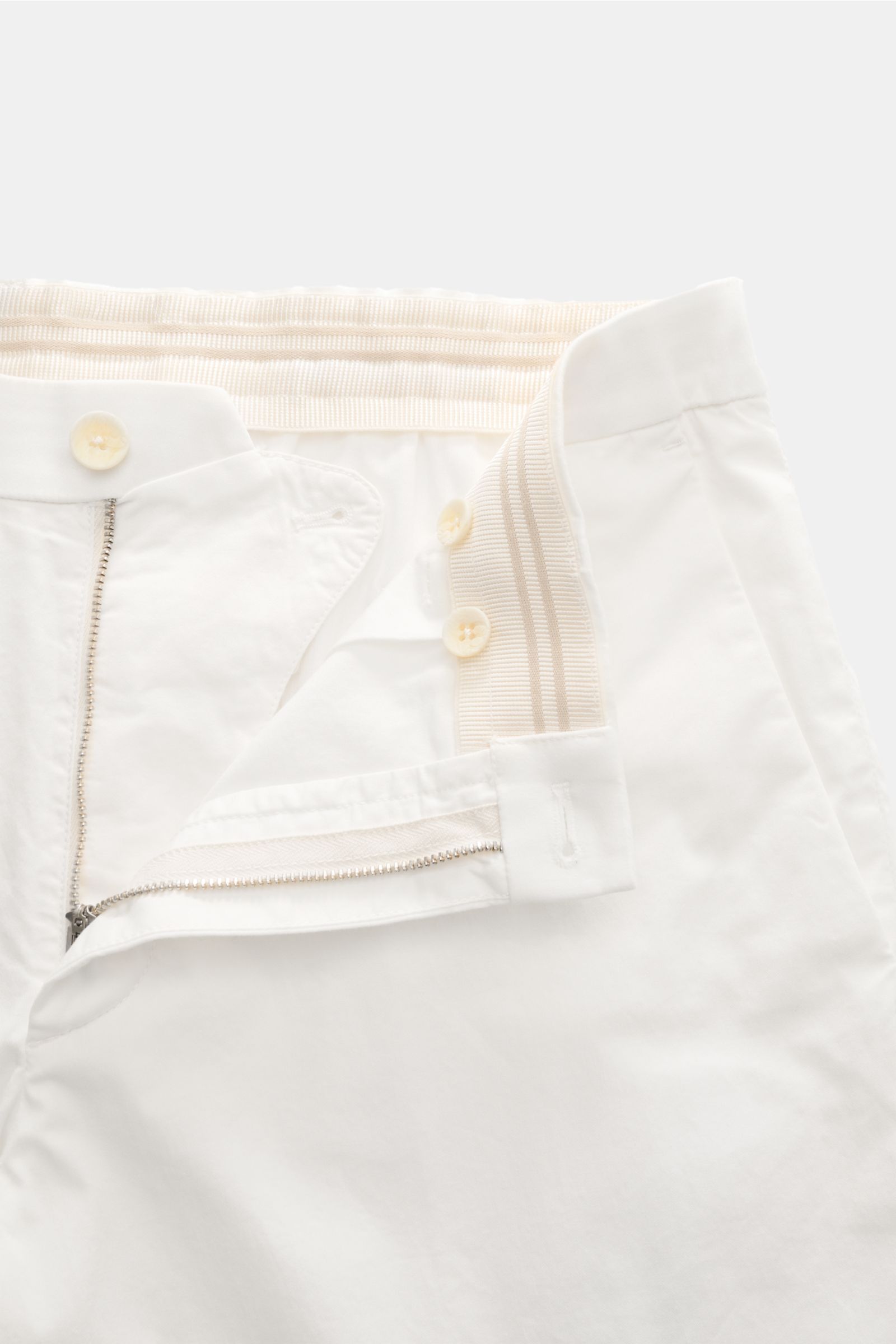 Close-up top-down view of the open waistband and zipper of the GTA Chino 'Davide' creme, highlighting elastic band, button, and smooth cotton twill fabric. 

