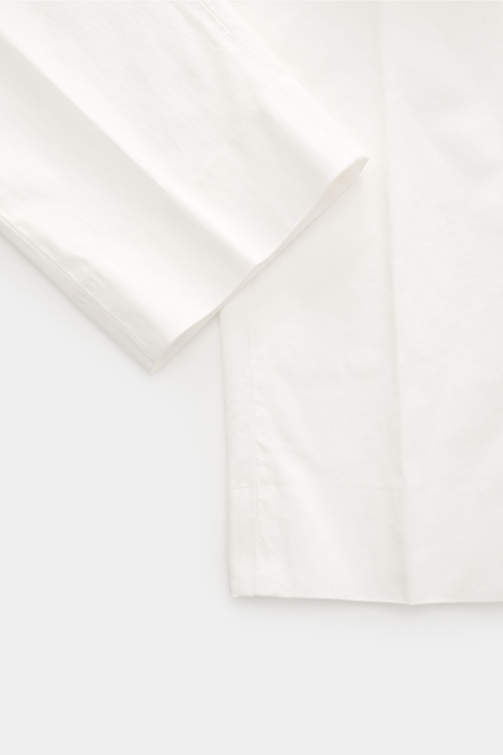 GTA Chino 'Davide' creme close-up of the sleeve and part of the pant leg, photographed from above, showing smooth, elastic cotton twill fabric with a regular fit and subtle details. 
