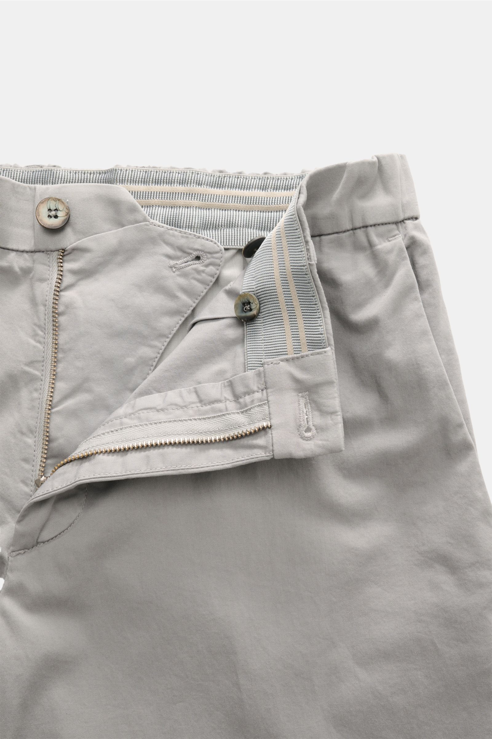 Close-up front view of the open waistband and zipper of the GTA Chino 'Davide' grau, showing twill cotton fabric, elastic waistband with striped detail, button and zipper closure, and smooth texture.


