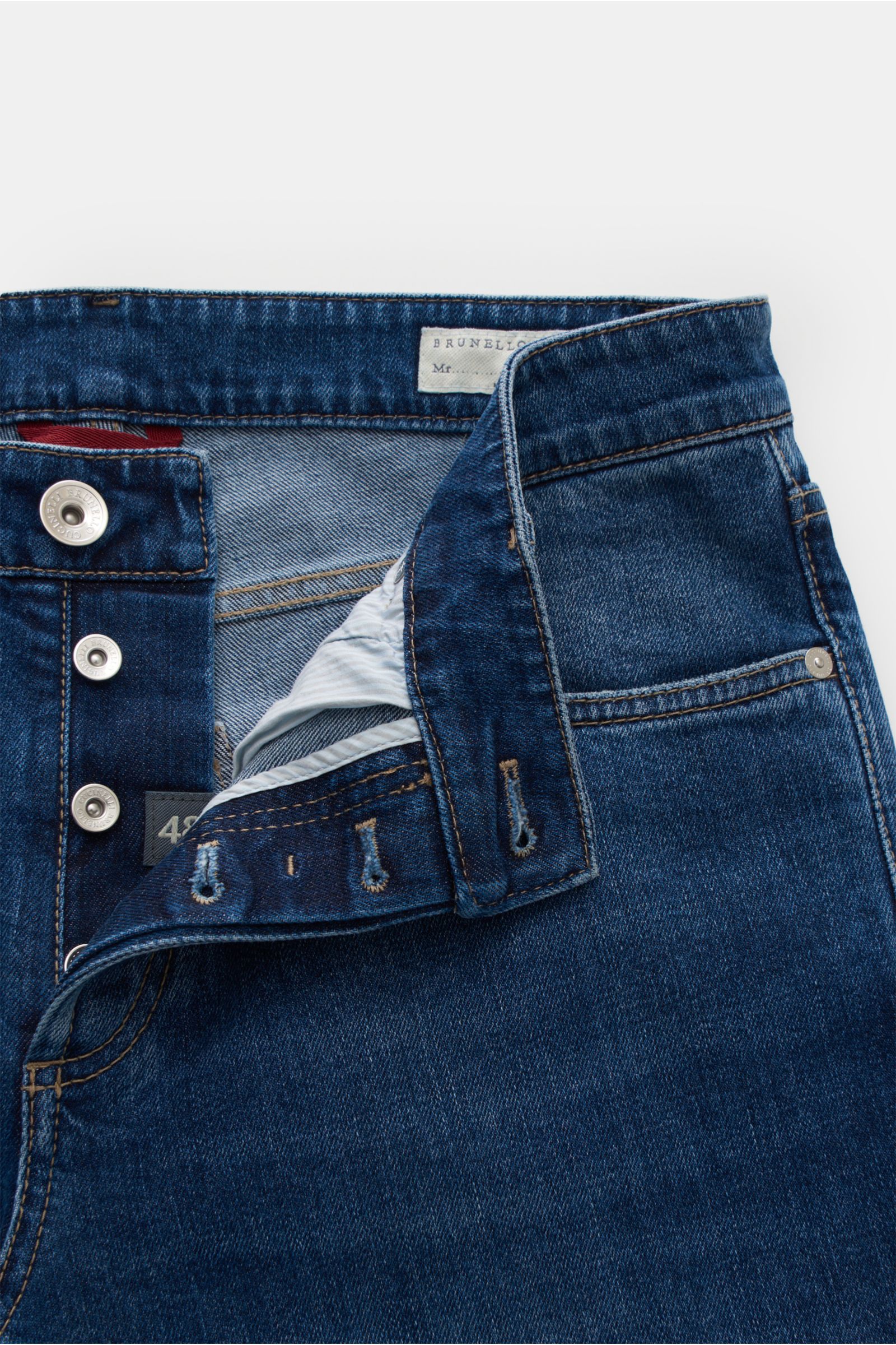 Brunello Cucinelli Jeans 'Traditional Fit' blau, Detailaufnahme von vorne mit offenem Button Fly, Five-Pocket-Stil, leichter Used-Waschung, softem Denim aus elastischer Baumwolle und genarbtem Leather Patch.