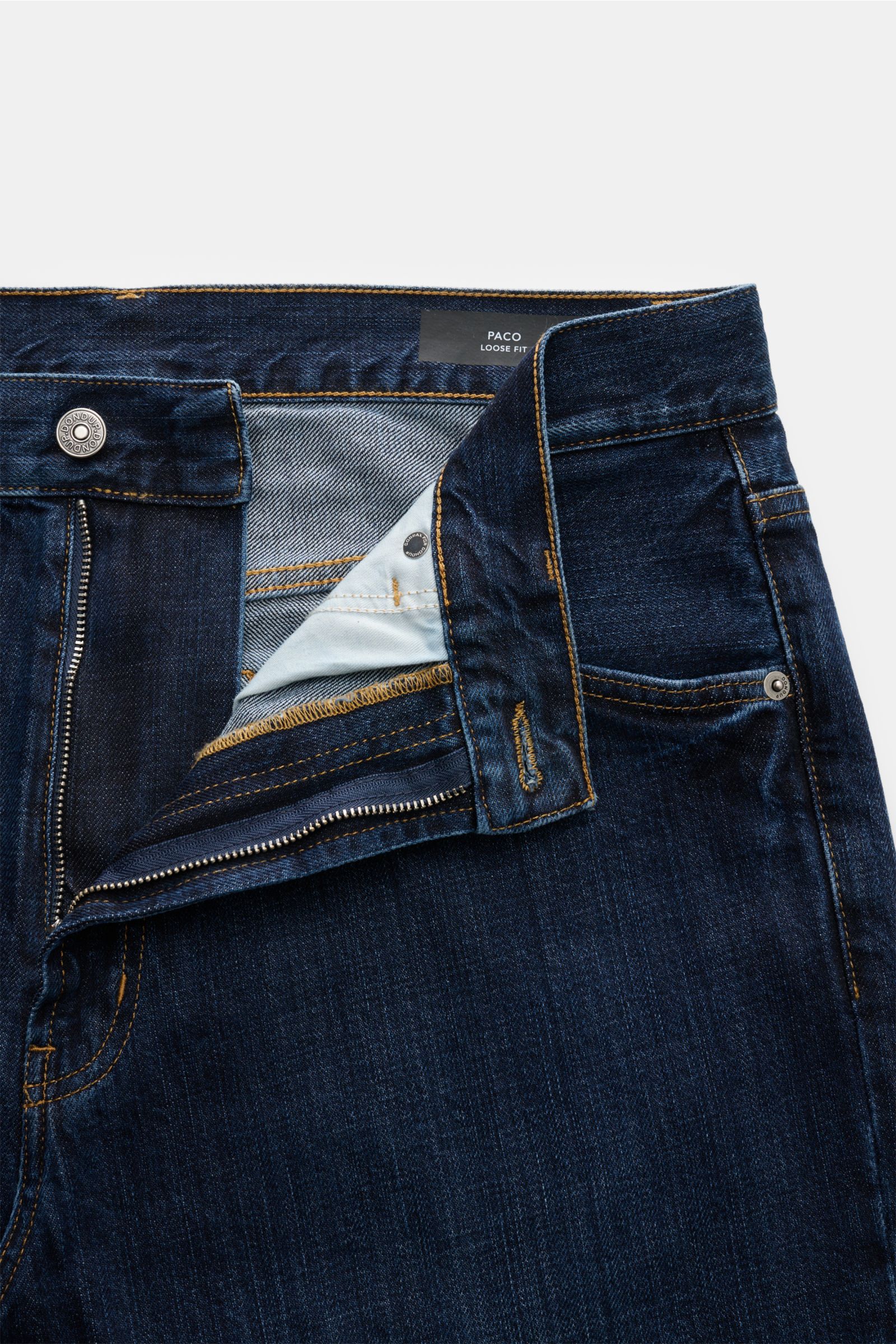 Close-up front view of Dondup Jeans 'Paco' navy showing zip fly, five-pocket style, typical metal initial, inside web patch, made of pure cotton denim with a slightly textured feel, tapered fit, regular thigh width, and ankle length.