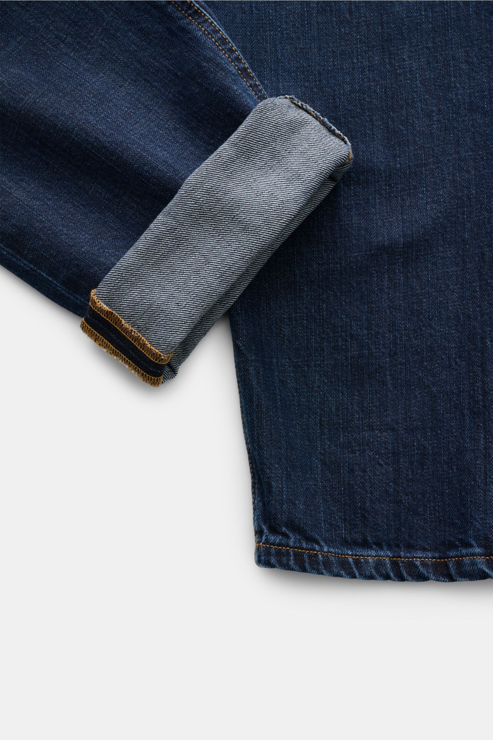 Close-up top-down view of the cuff and lower leg of Dondup Jeans 'Paco' navy, showing denim aus reiner Baumwolle, leicht griffige Haptik, Tapered Fit, reguläre Oberschenkelweite, knöchellang, Zip Fly, Five-Pocket-Stil, typisches Metall-Initial, innenliege