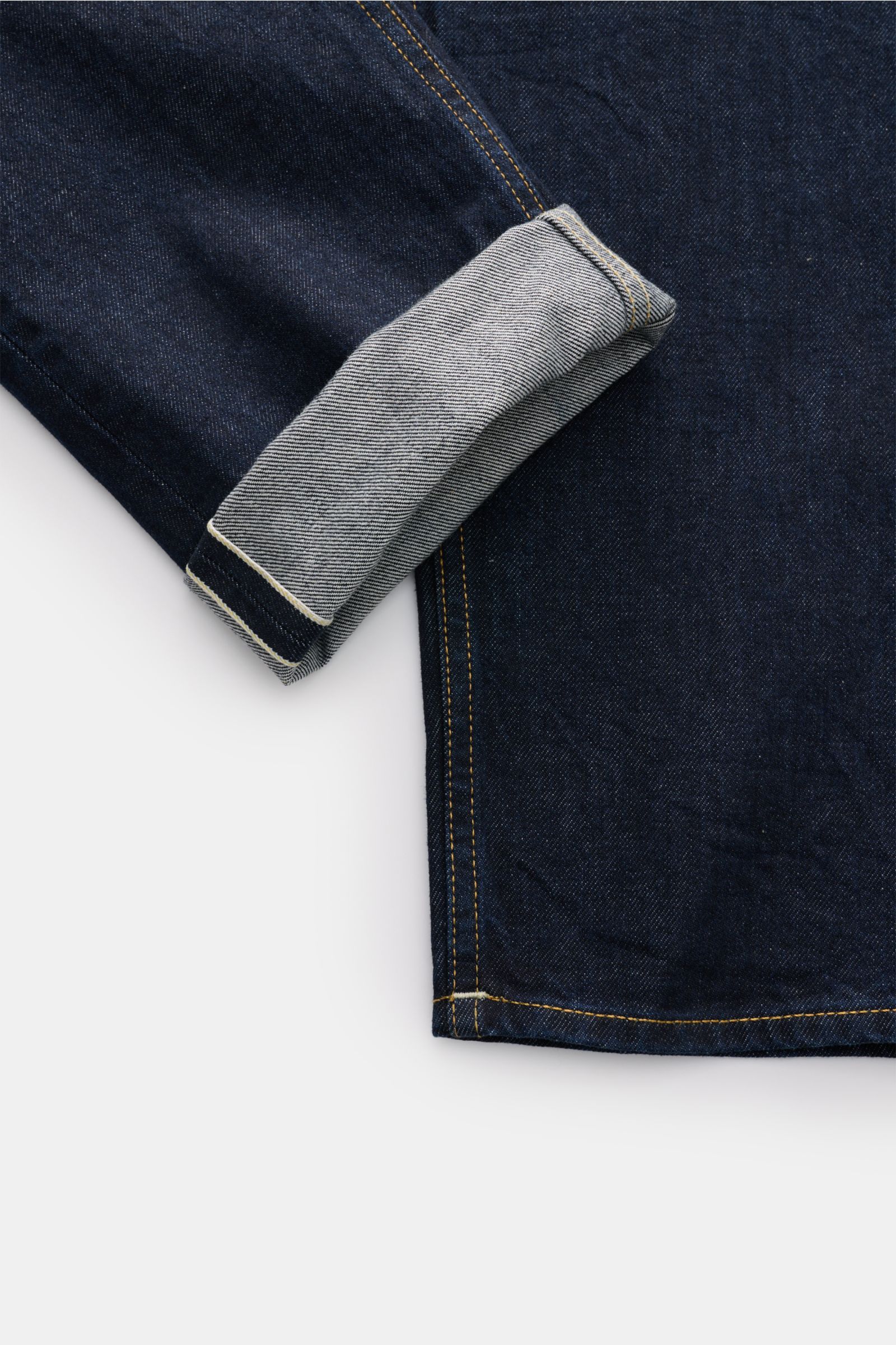 Closed Jeans 'Cooper' dark navy shown from a close-up top-down perspective, highlighting the folded hem and textured pure cotton denim.  

Die Slim Fit Jeans 'Cooper' vom Hamburger Denim-Label CLOSED wurde aus reiner Baumwolle im Raw-Design gefertigt u