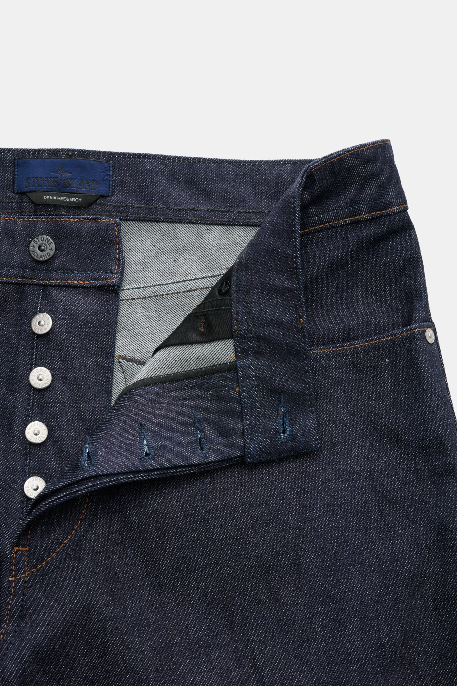 Stone Island Jeans 'Indigo Denim - Raw' navy mit offenem Button Fly, Five-Pocket-Stil, geradem Schnitt und Kompass-Badge am Bund, Detailansicht.